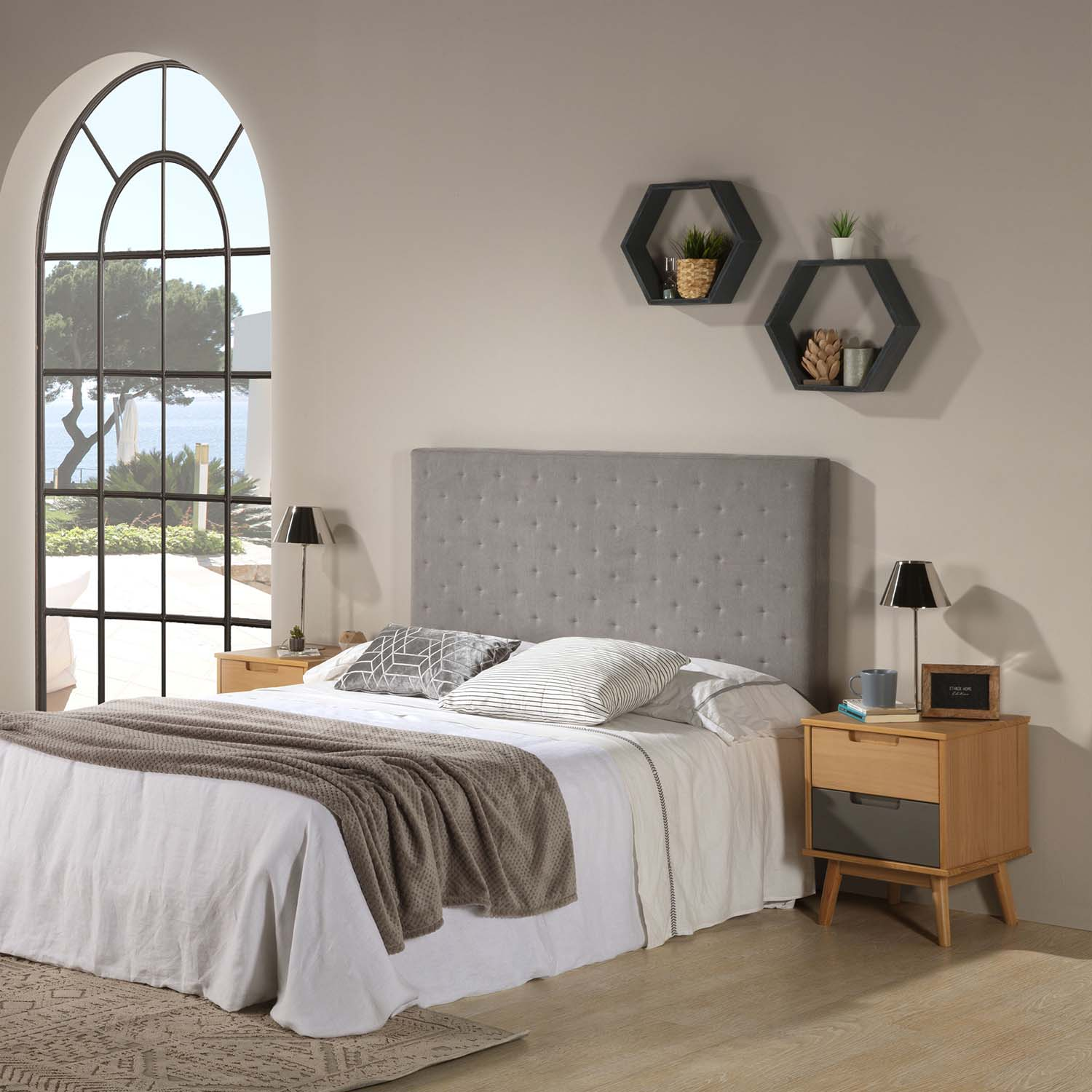 Un dormitorio con cama grande, dos mesitas de noche y vistas a ventana arqueada.