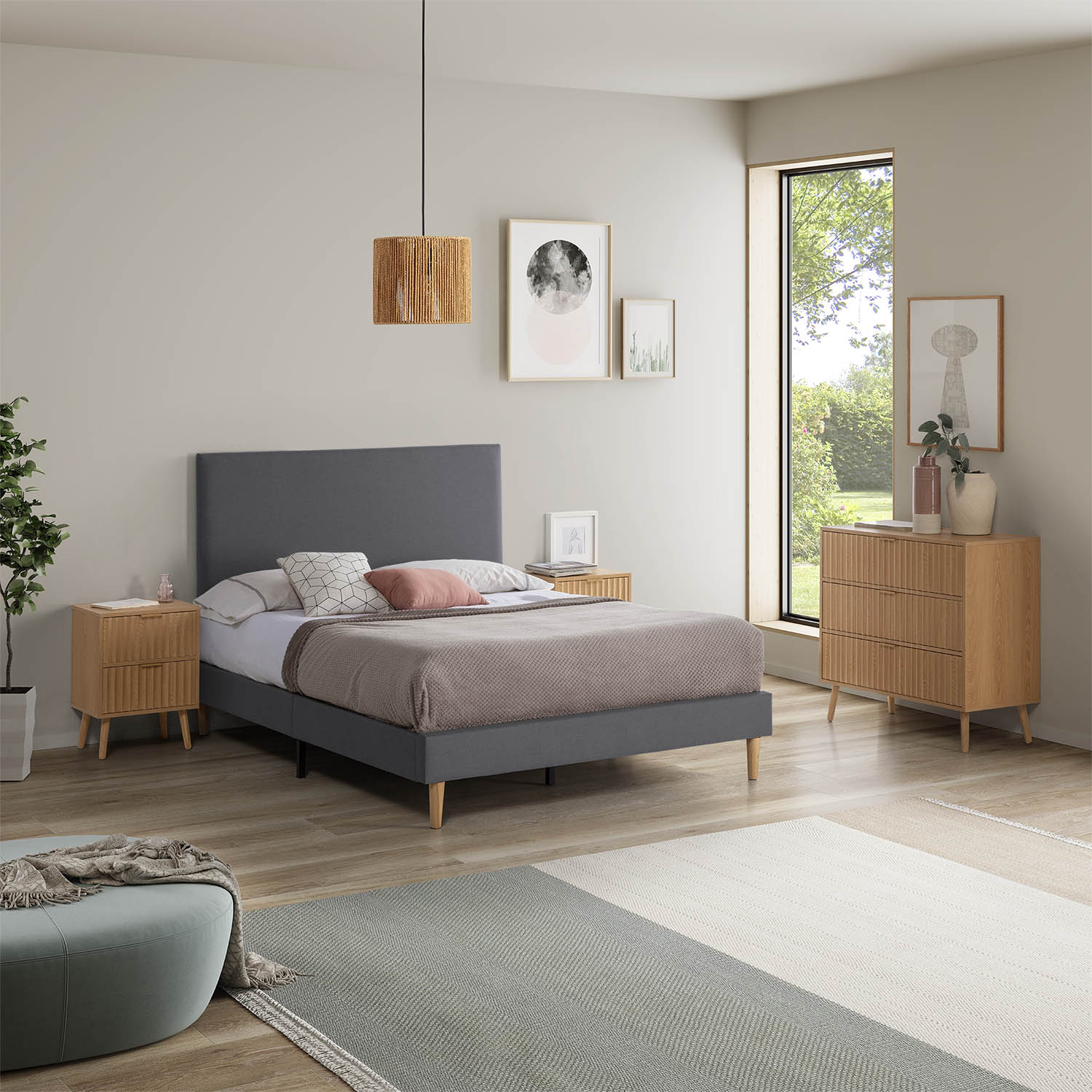 Un dormitorio con cama gris, mesitas de noche de madera y cómoda con vista a ventana.