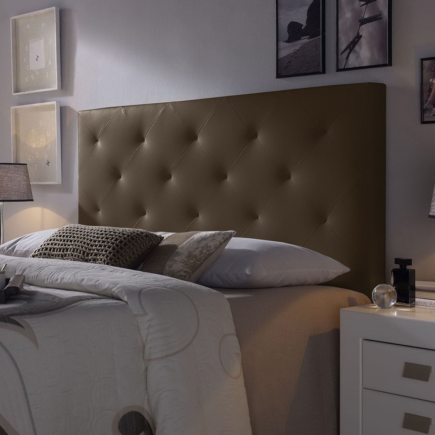 Un cabecero marrón acolchado sobre una cama con almohadas y mantas.