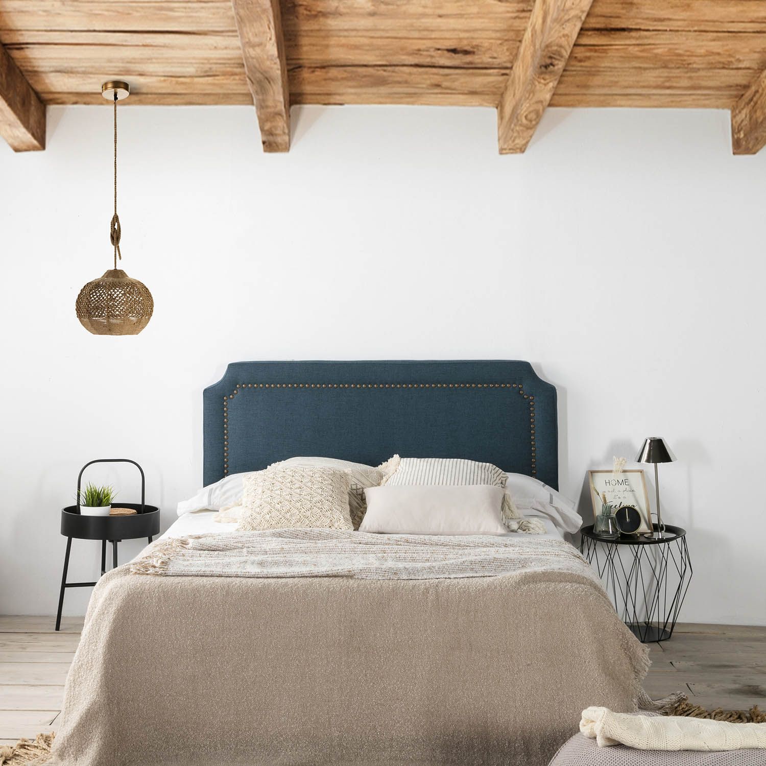 Un dormitorio acogedor con cabecero azul verdoso, ropa de cama mullida y vigas de madera.