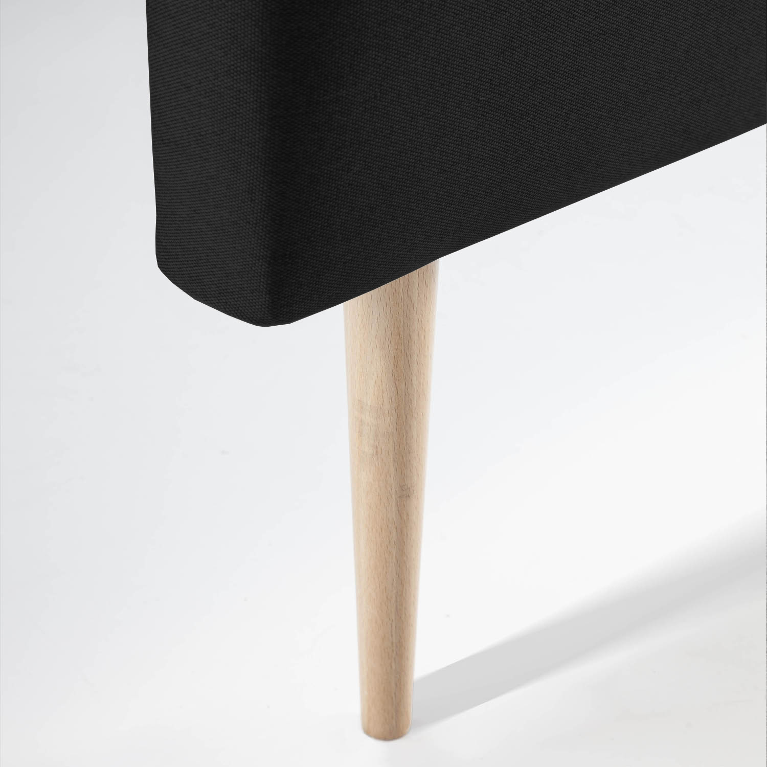 Primer plano de un mueble negro con una sola pata de madera sobre fondo blanco.