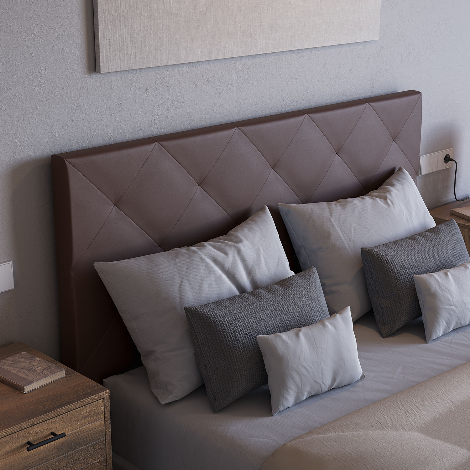 Vista de cerca de una cama con cabecero marrón de rombos cosidos, almohadas blancas y grises.