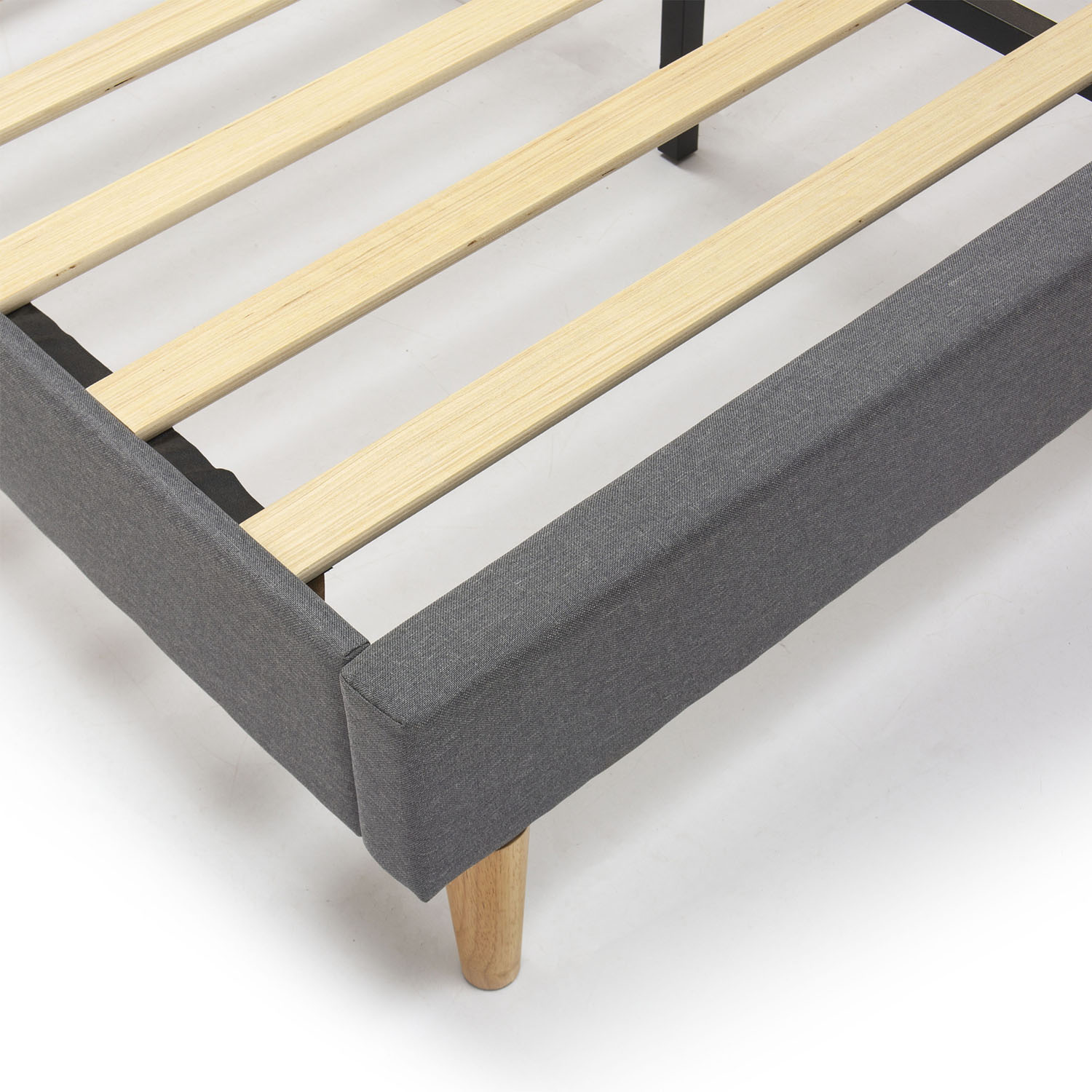 Primer plano de un somier tapizado gris con lamas y patas de madera.
