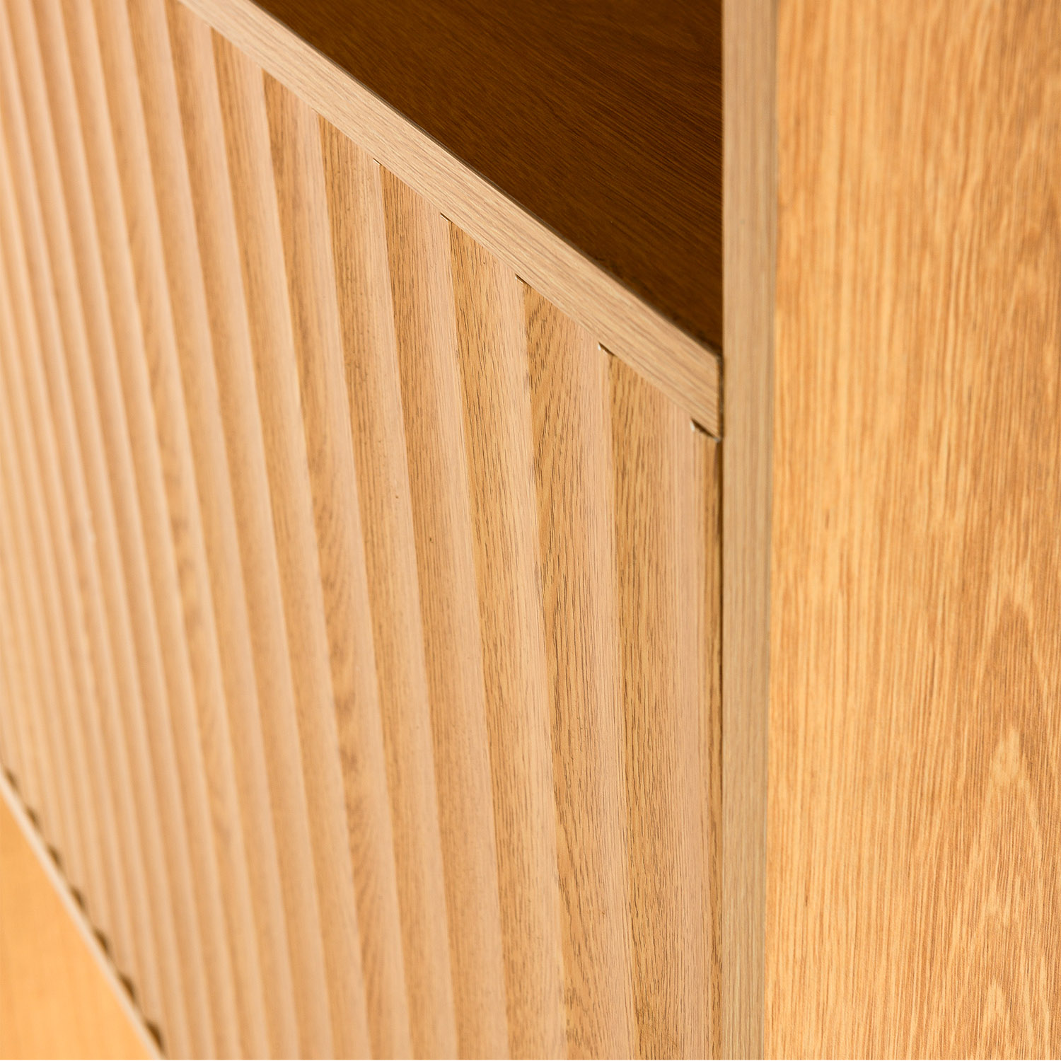Panel de madera con ranuras verticales junto a una superficie de madera lisa.