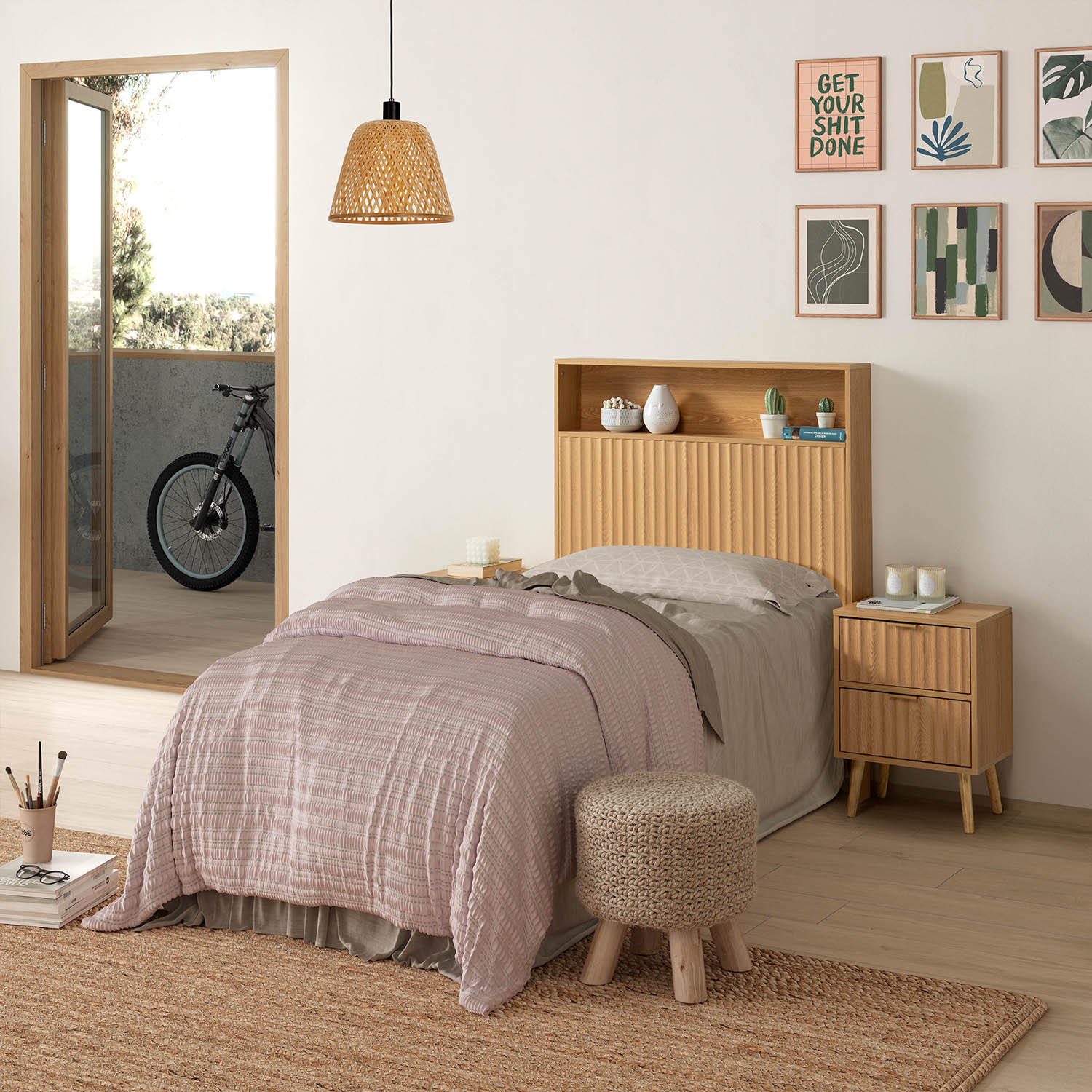 Dormitorio con colcha rosa, muebles de madera y láminas en la pared.