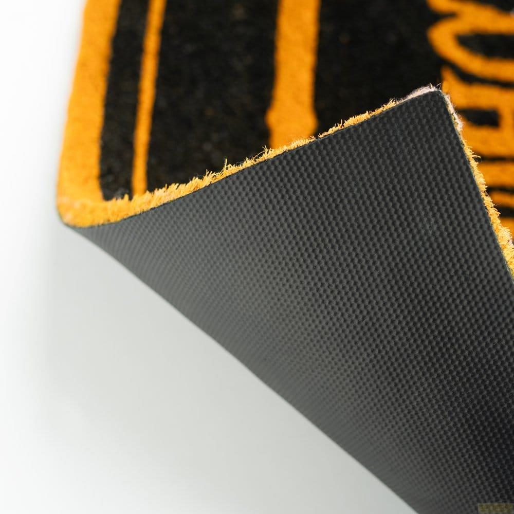 Primo piano di un tappeto nero con strisce arancioni, che mostra il retro gommato.