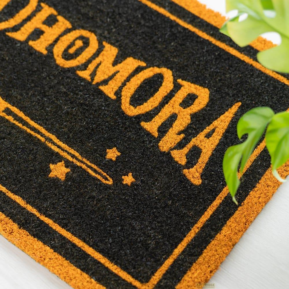Tappetino nero con scritta arancione "HOMORA" e simbolo di bacchetta.
