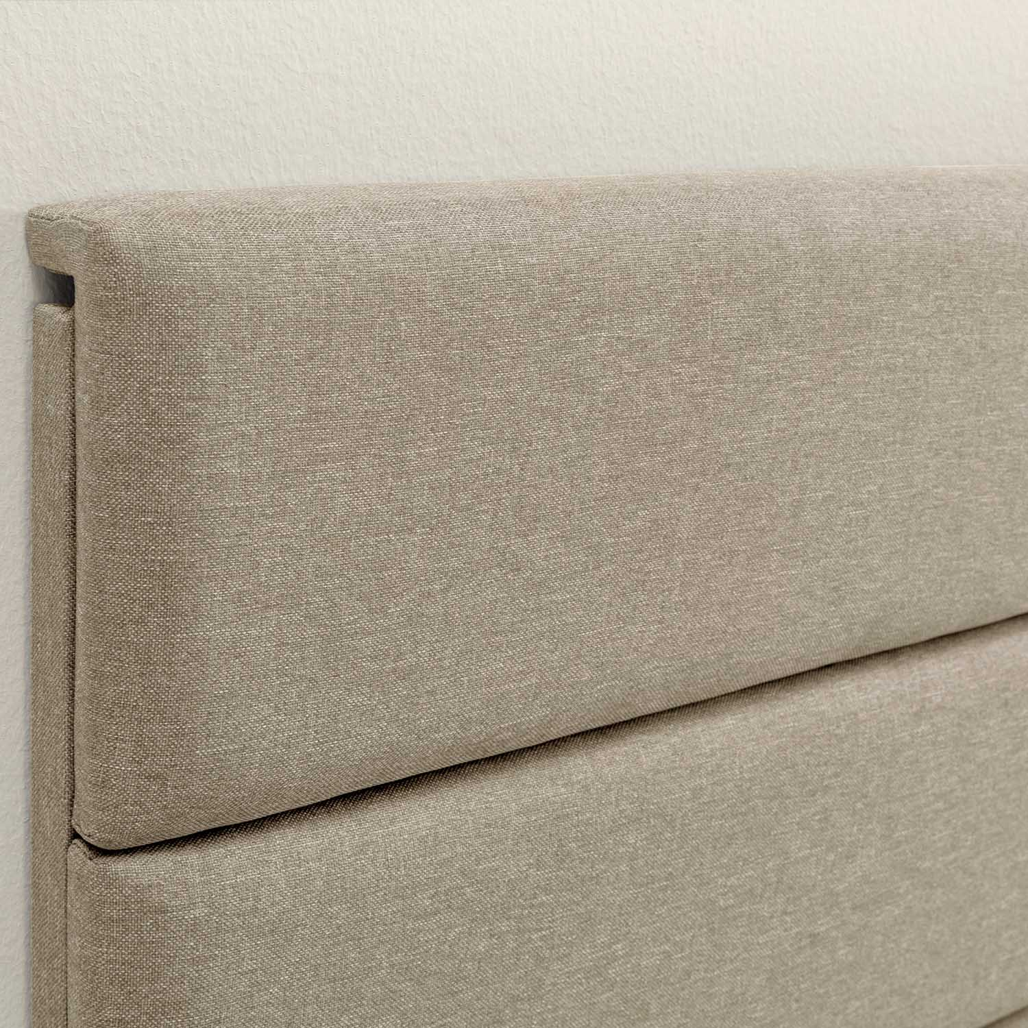 Cabecero de tela beige con dos secciones horizontales, contra una pared blanca.