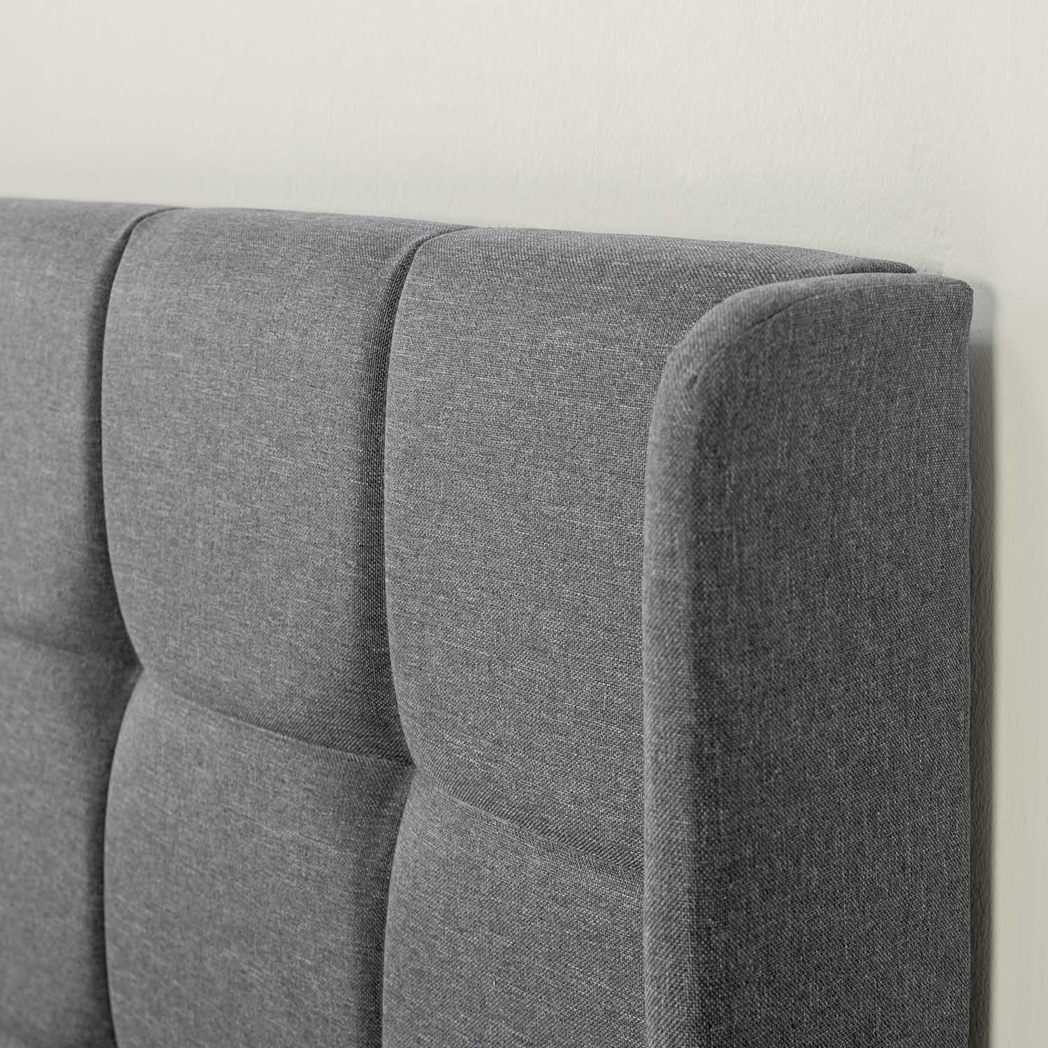 Respaldo de cama tapizado gris con costuras verticales y cuadrados acolchados.