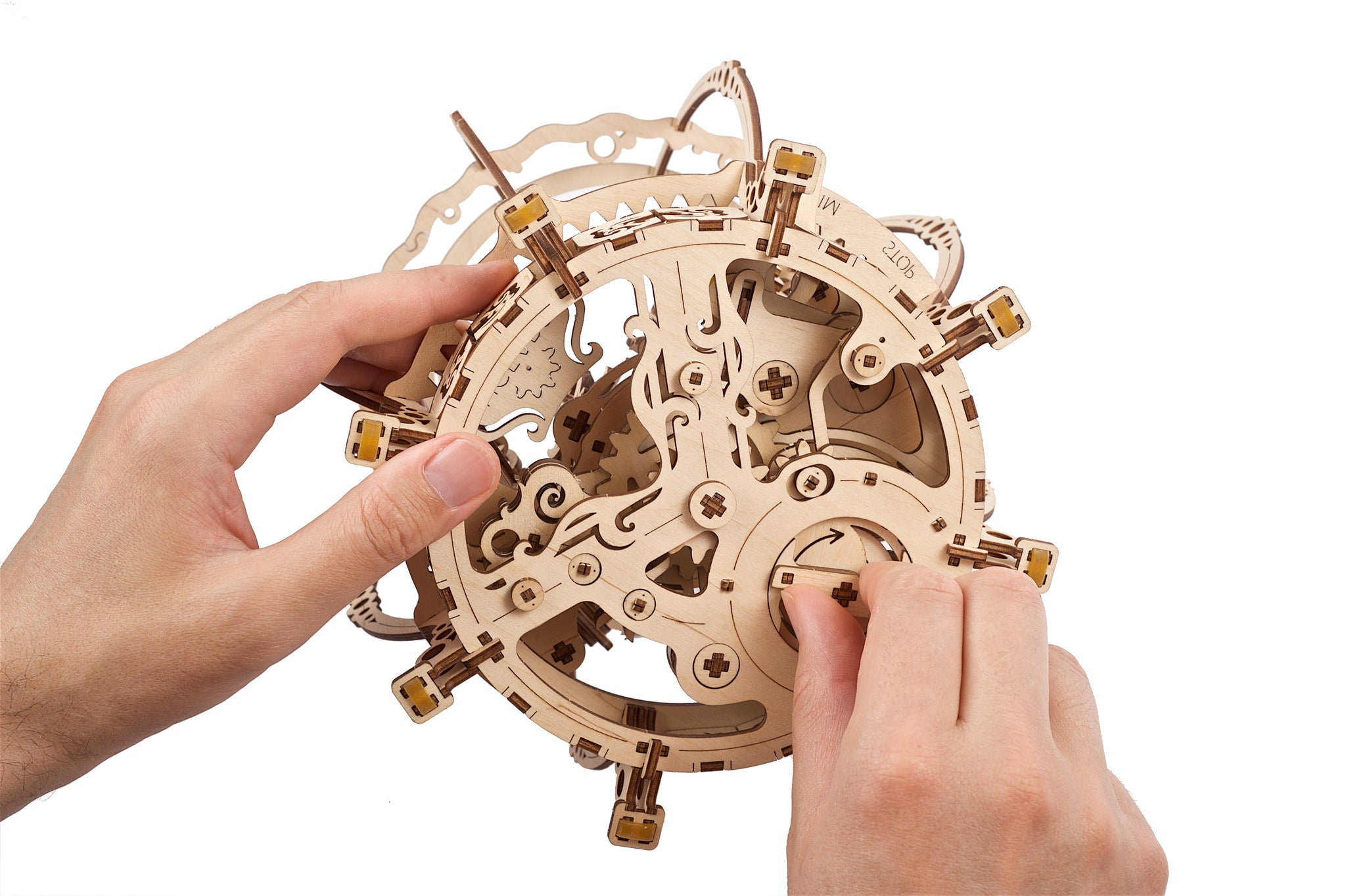 Des mains assemblent un modèle mécanique complexe en bois avec engrenages et leviers.