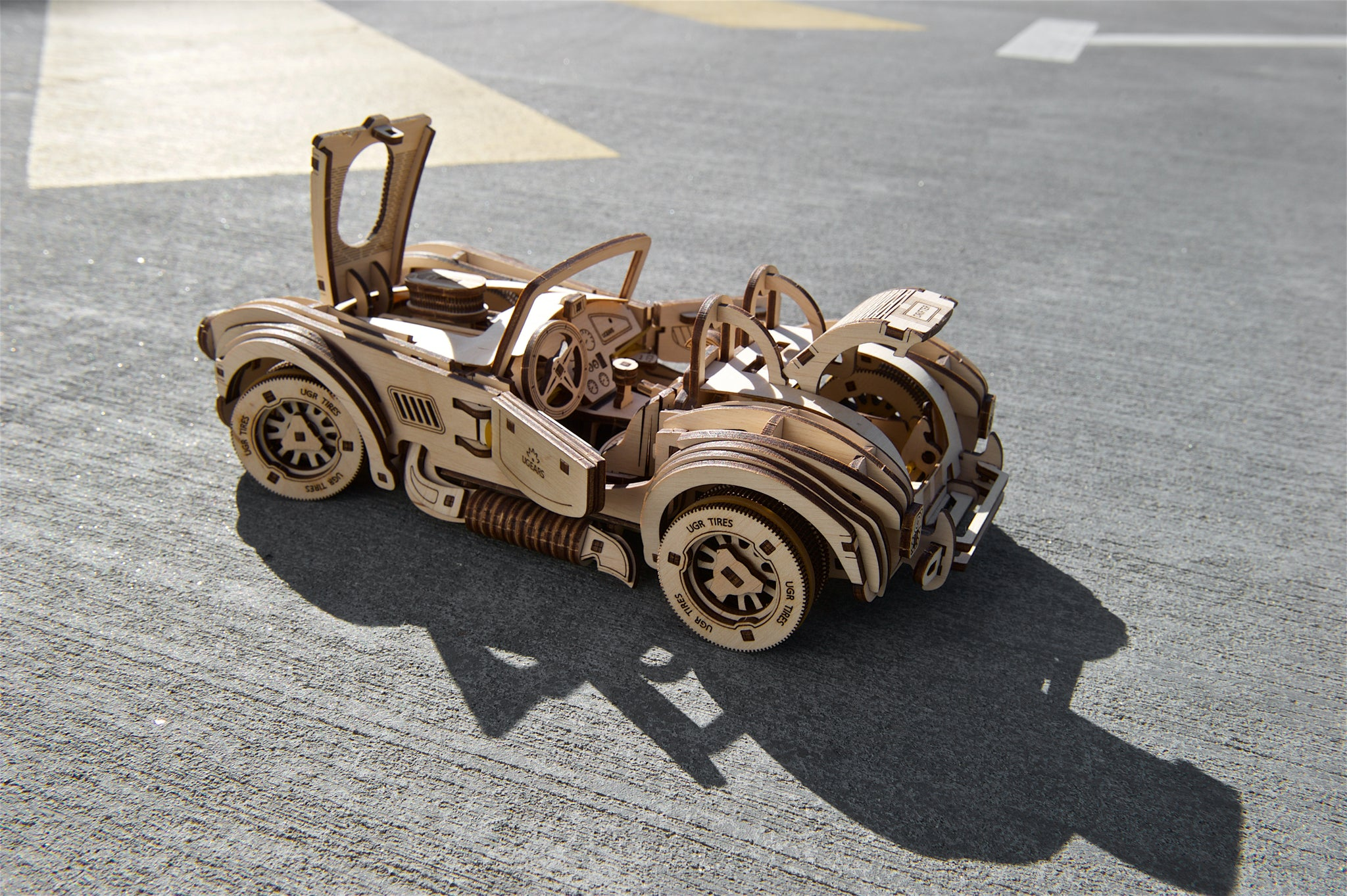 Ein detailliertes Holzmodell eines Autos mit geöffneten Türen und Haube.