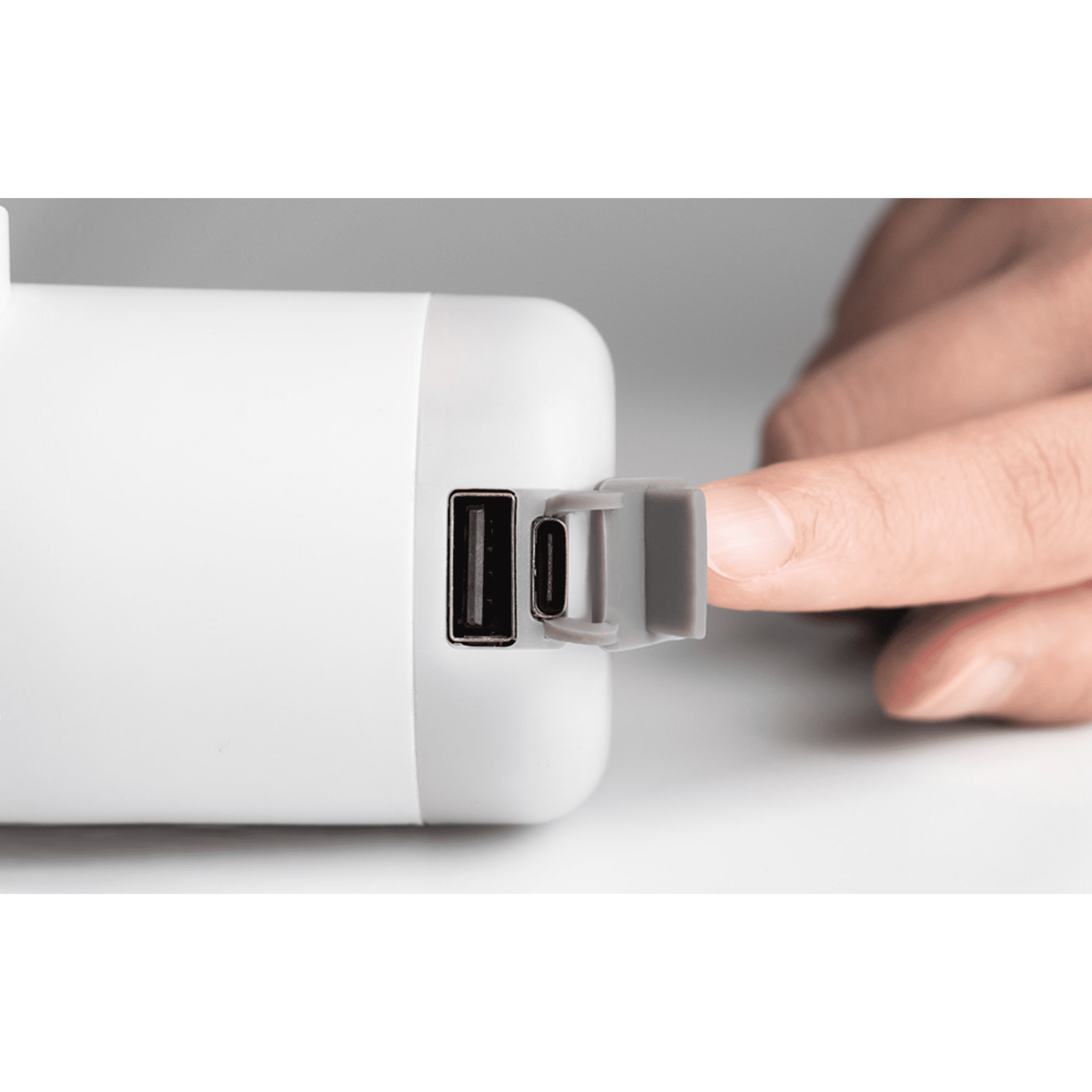 Ein Finger öffnet die Klappe eines weißen Ladekabels mit USB-A- und USB-C-Anschlüssen.