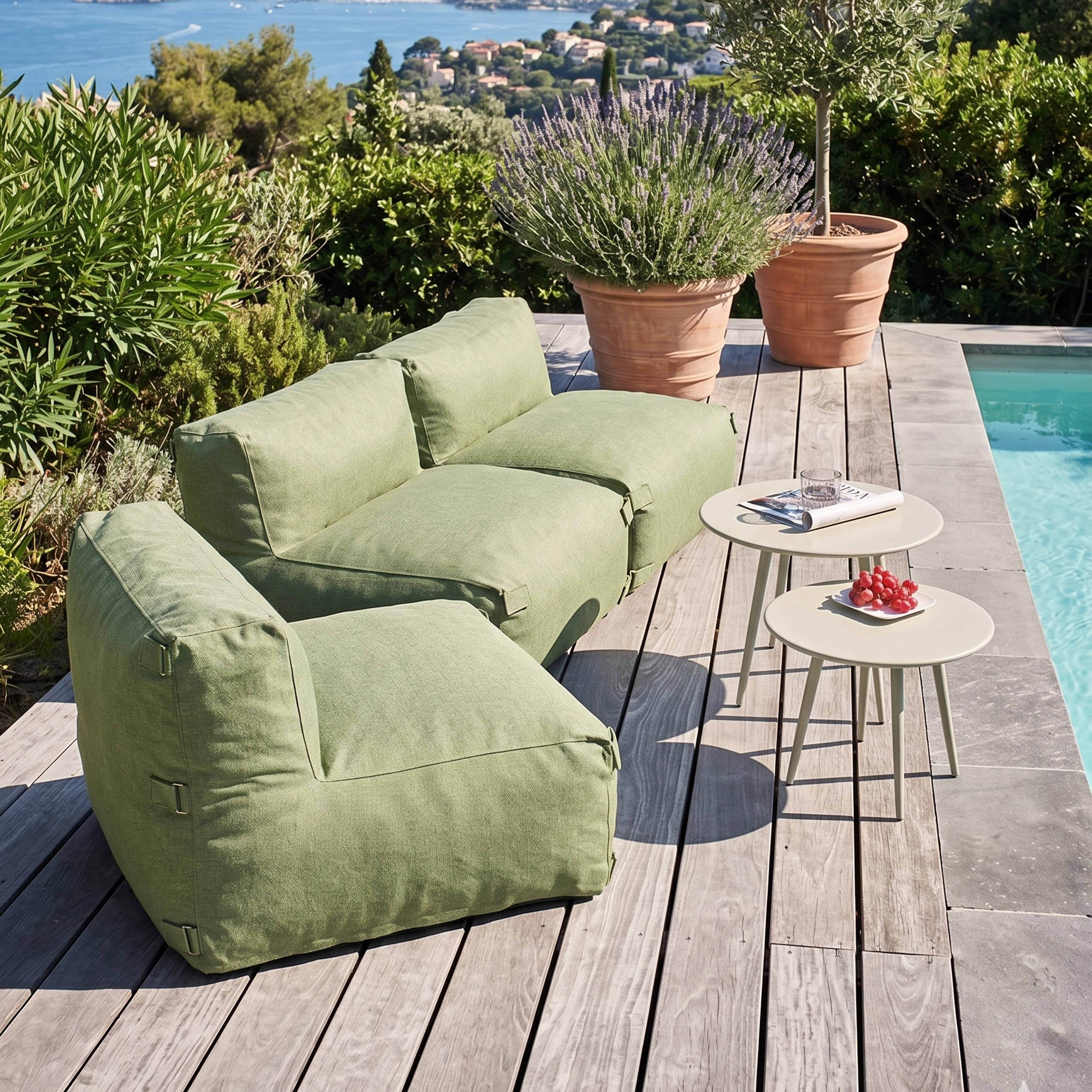 Grünes Loungesofa am Pool mit zwei Beistelltischen, Trauben und Aussicht.
