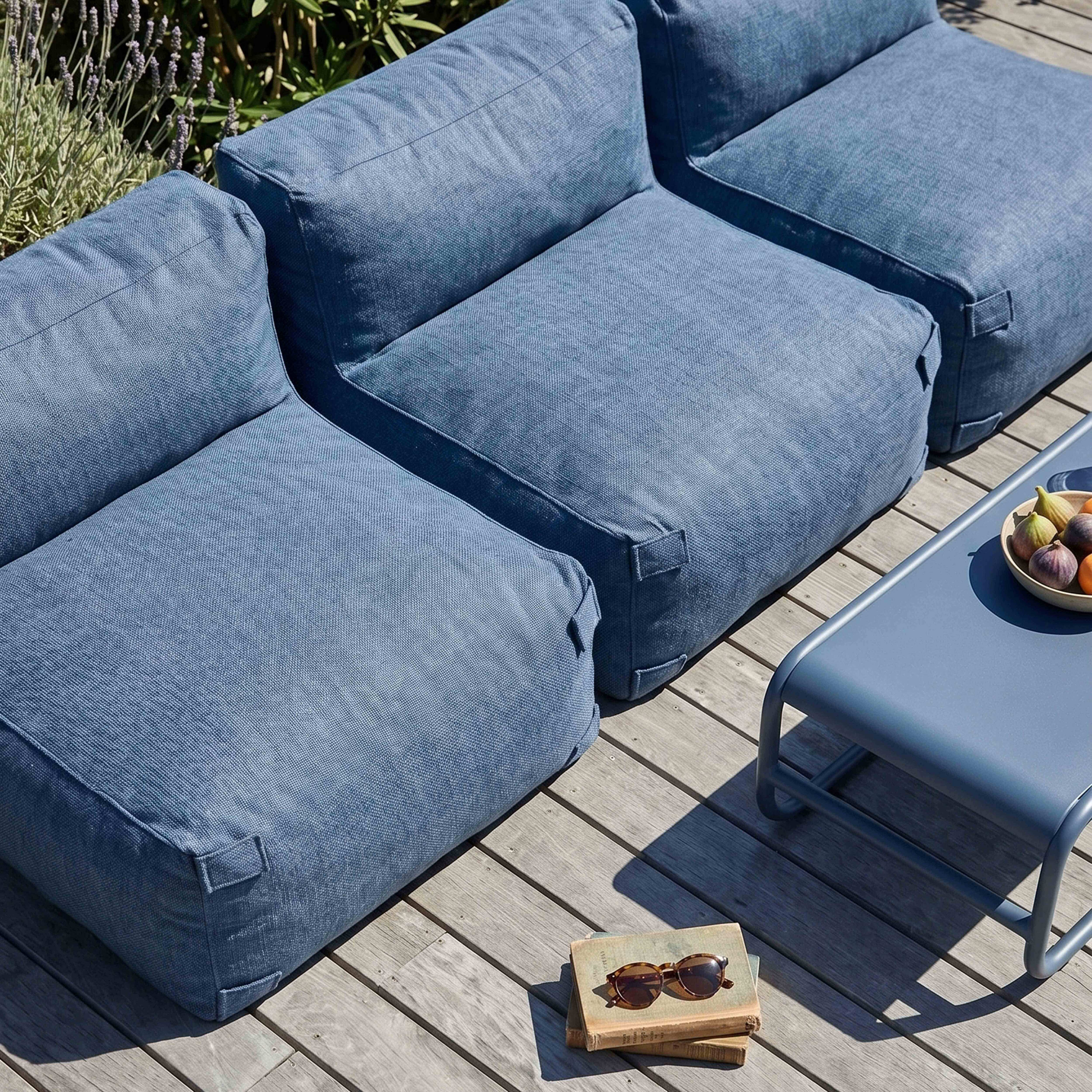 Blaue Gartenmöbel auf Holzdeck mit Obstschale und Büchern.