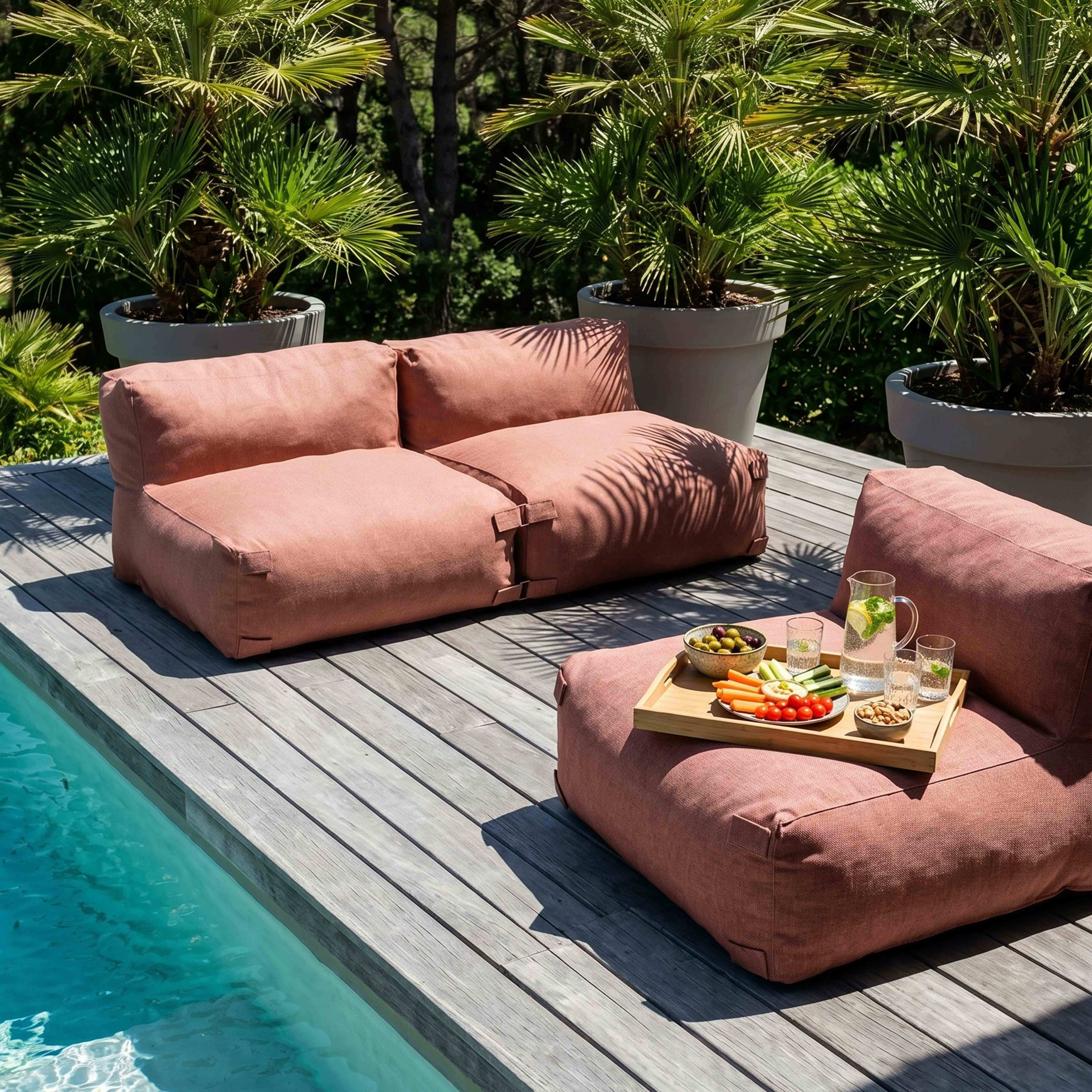 Rosa Loungemöbel am Pool mit Snack-Tablett und Palmen.