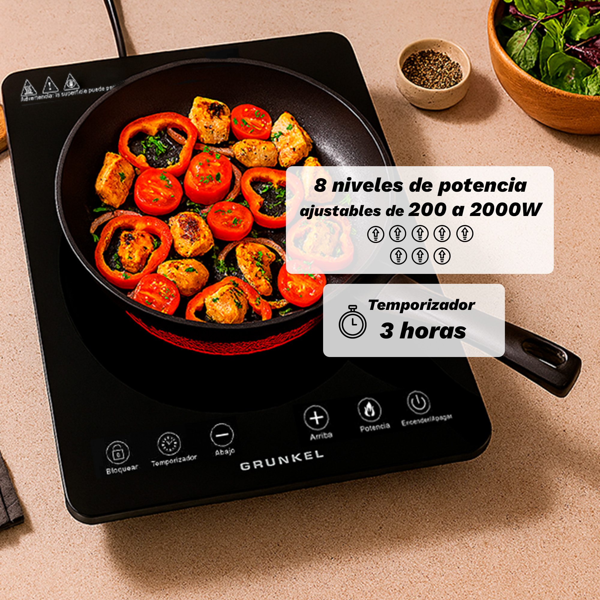 Una placa de inducción con una sartén de pollo, pimientos y tomates.