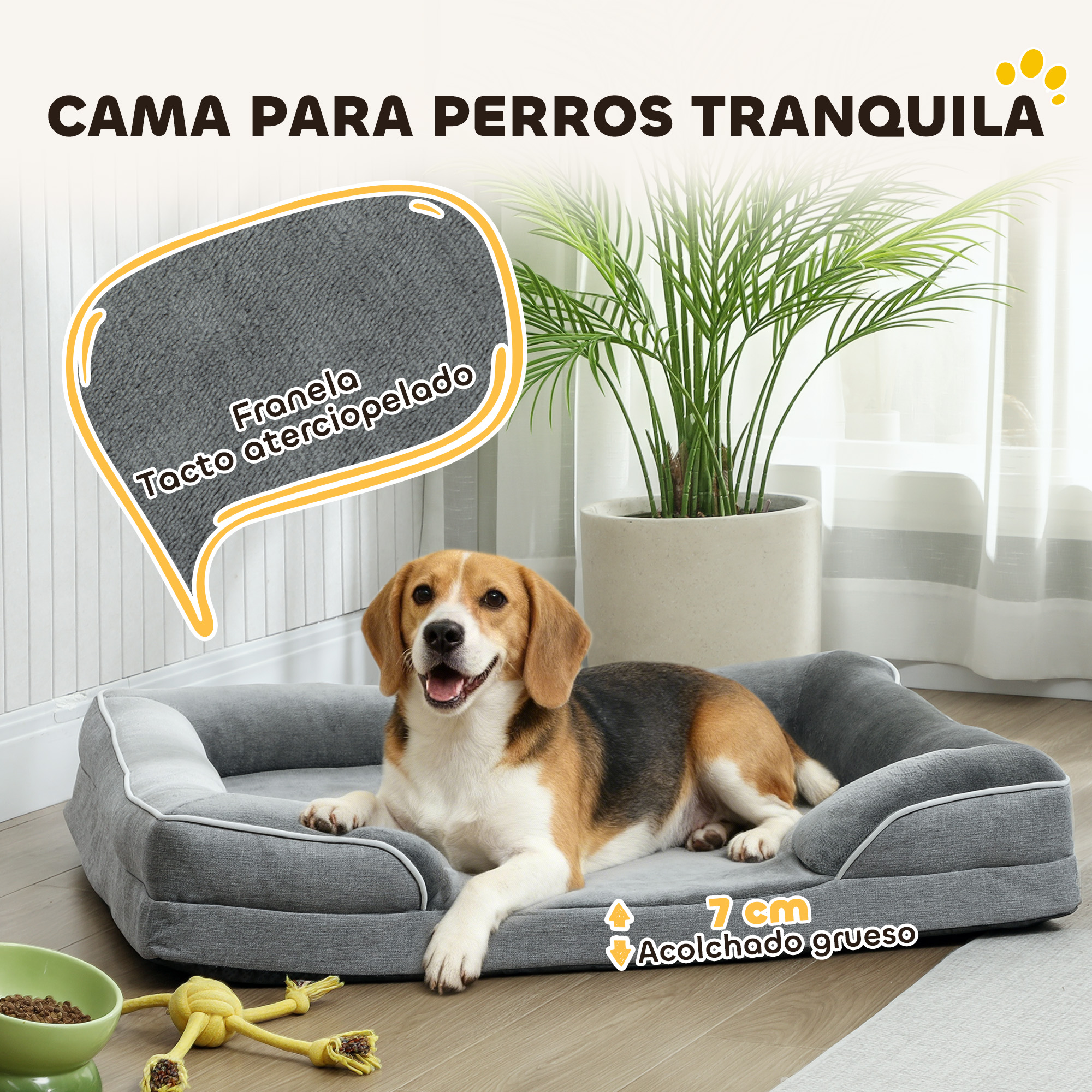 Un beagle descansa en una cama gris para perros. Cerca hay un juguete y un cuenco.