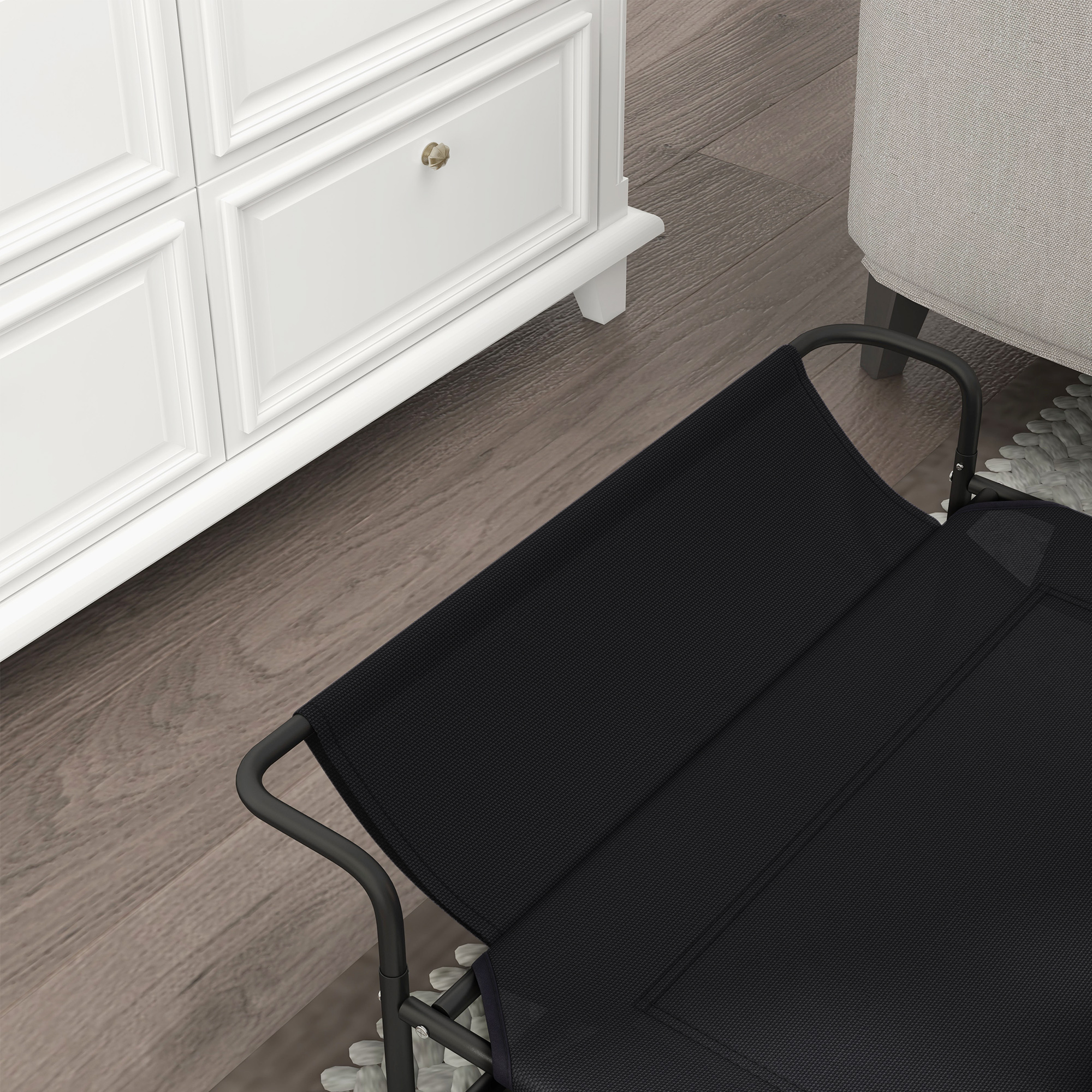 Una silla de tela negra con marco de metal junto a una cómoda blanca.
