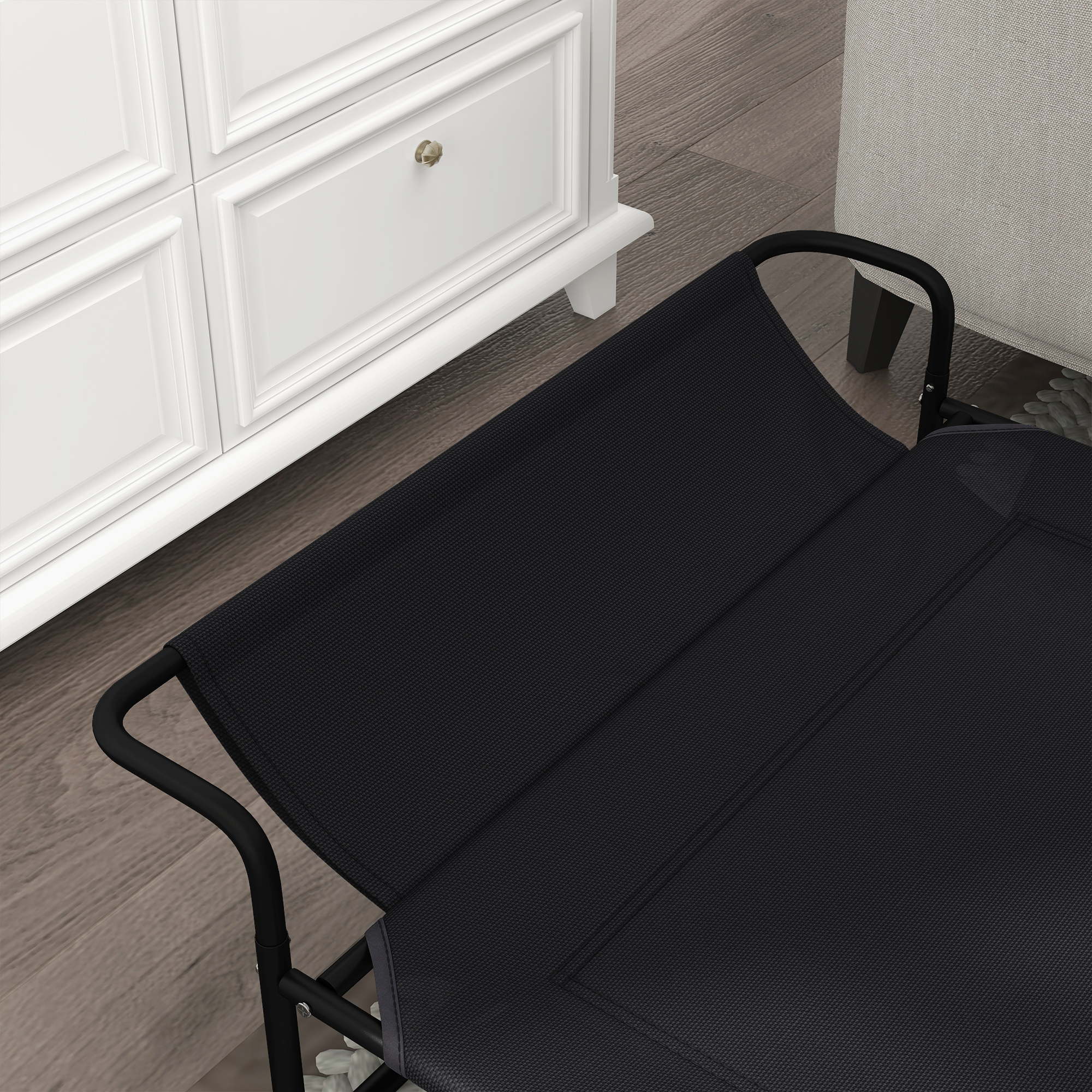 Una silla plegable negra junto a un armario blanco y un sillón gris claro.