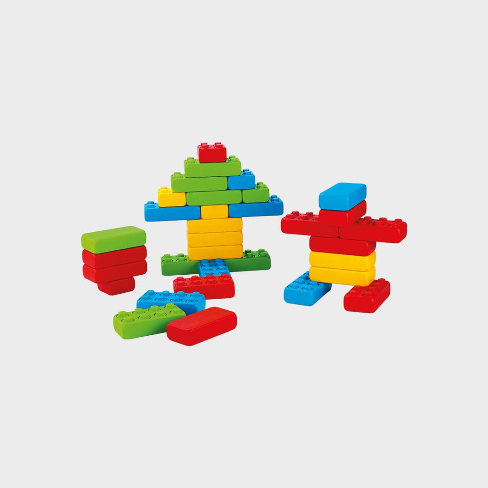 Bloques de construcción coloridos forman una figura y un árbol sobre fondo gris.