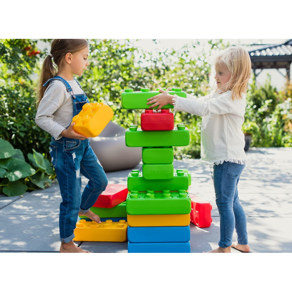 Dos niñas construyen una torre de bloques coloridos en el jardín.
