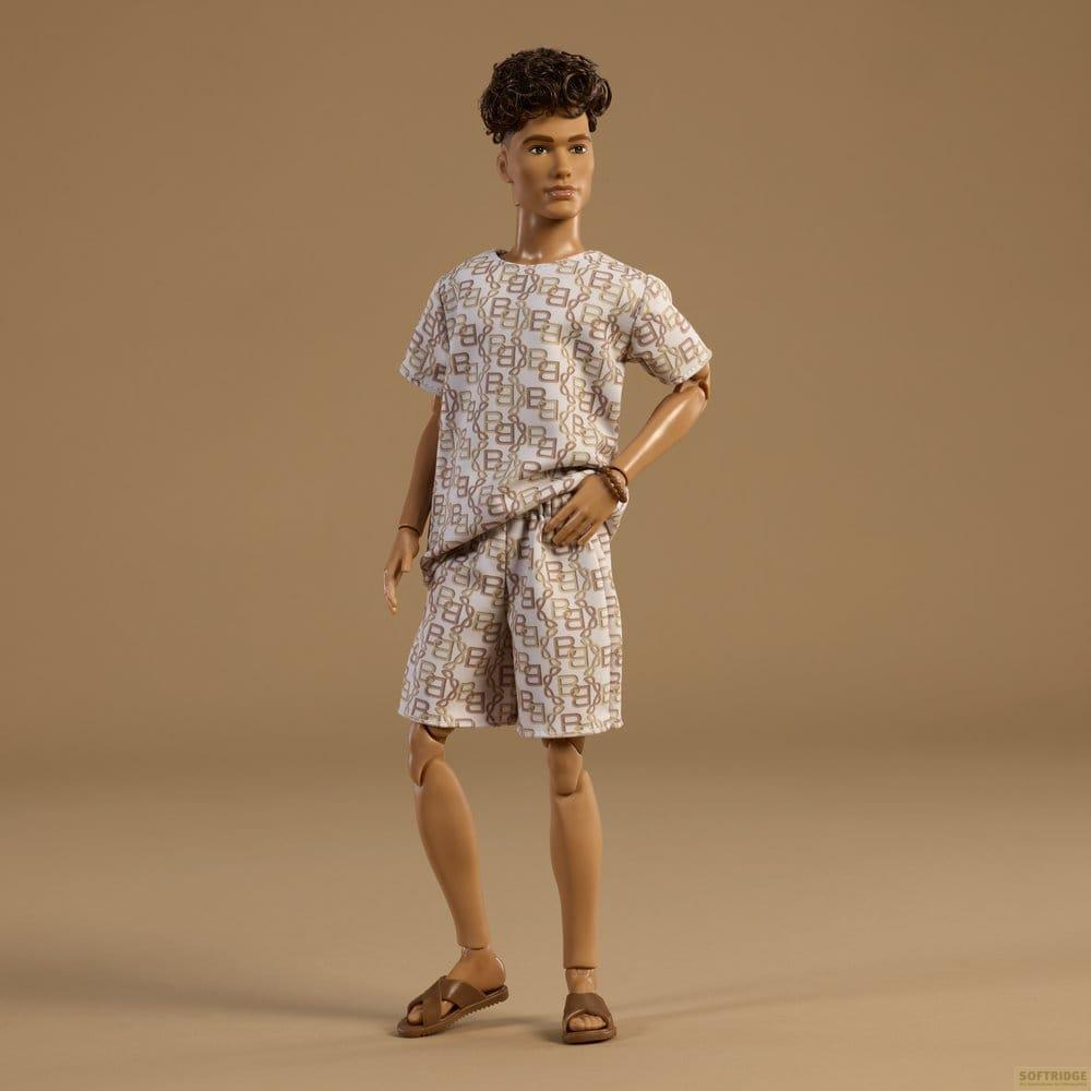 Eine Puppe mit braunem, lockigem Haar trägt ein weißes T-Shirt und Shorts mit braunem Muster.