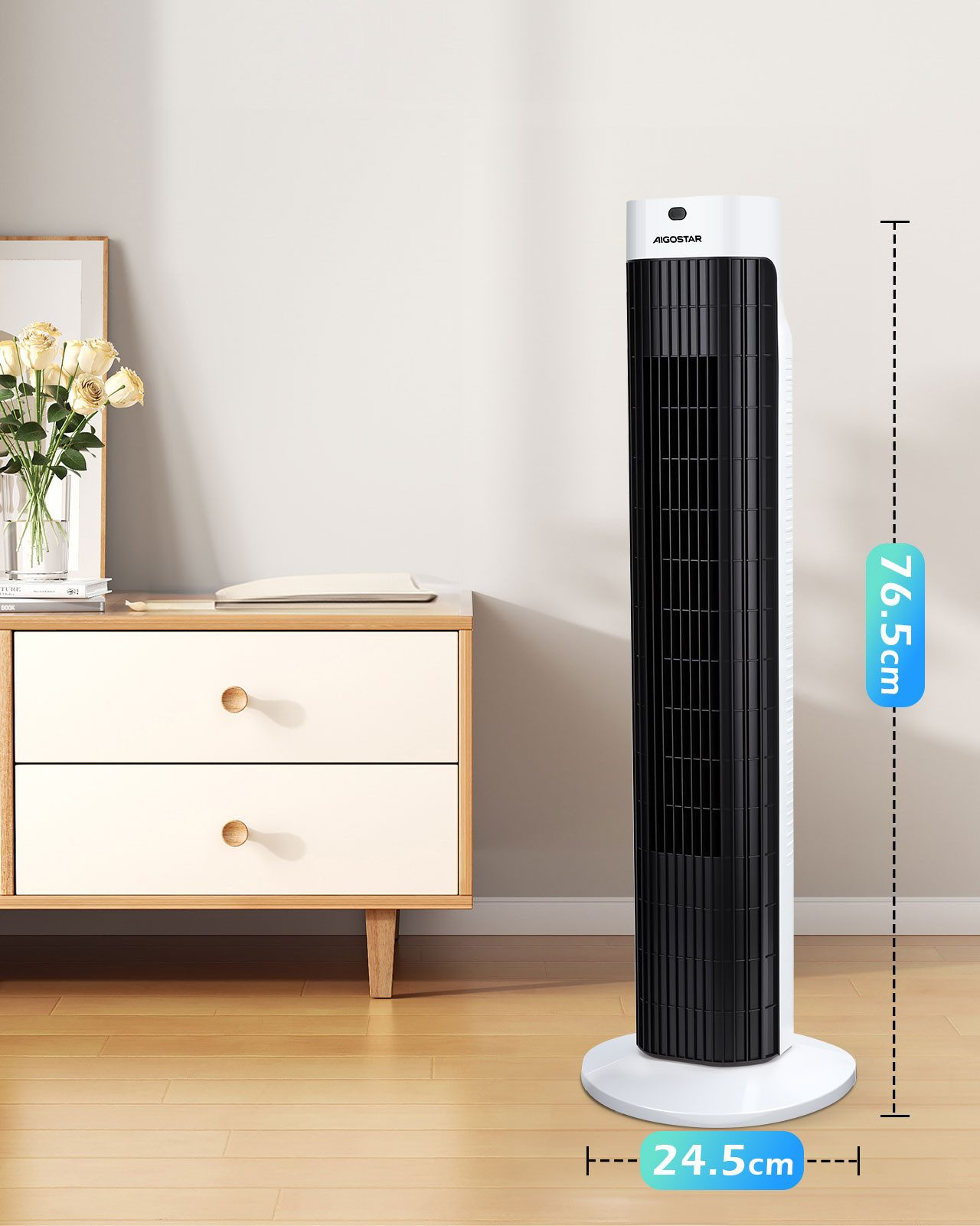 Ein schlanker, weißer und schwarzer Turmventilator steht neben einer Kommode mit Blumen.