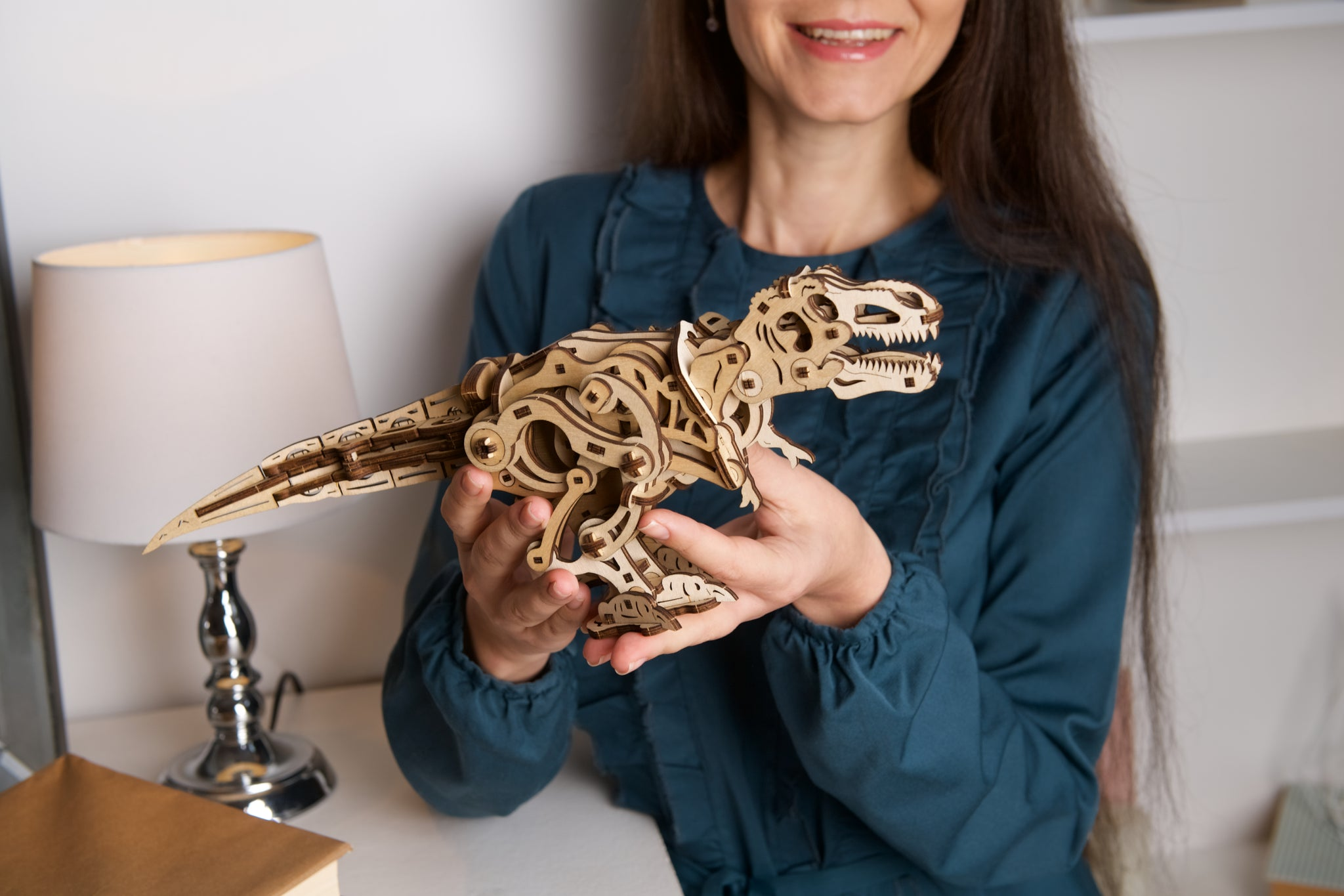 Una donna tiene un puzzle di dinosauro in legno.