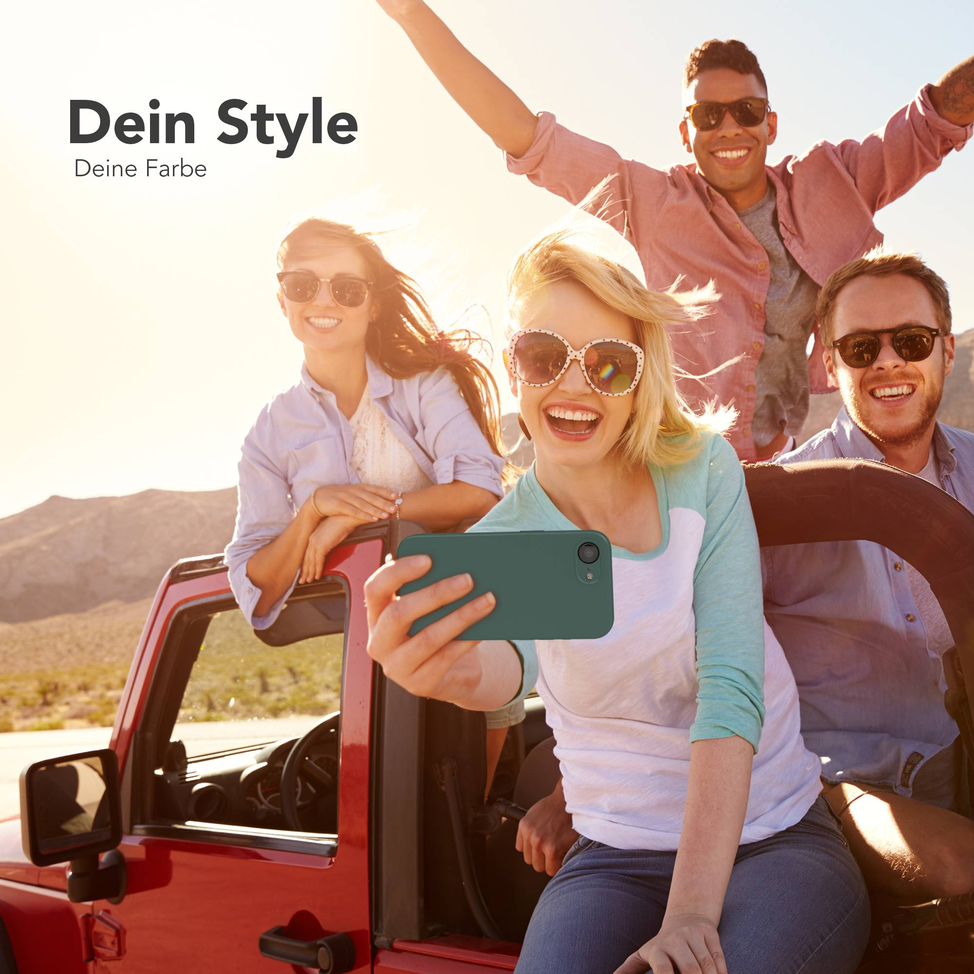 Vier Freunde in einem roten Jeep machen ein Selfie im sonnigen Wüstenlandschaft.