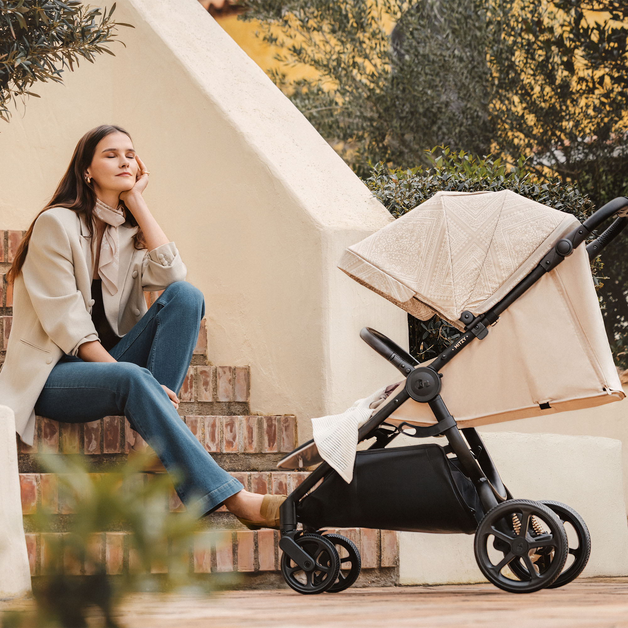 Eine Frau sitzt auf einer Treppe neben einem Kinderwagen.