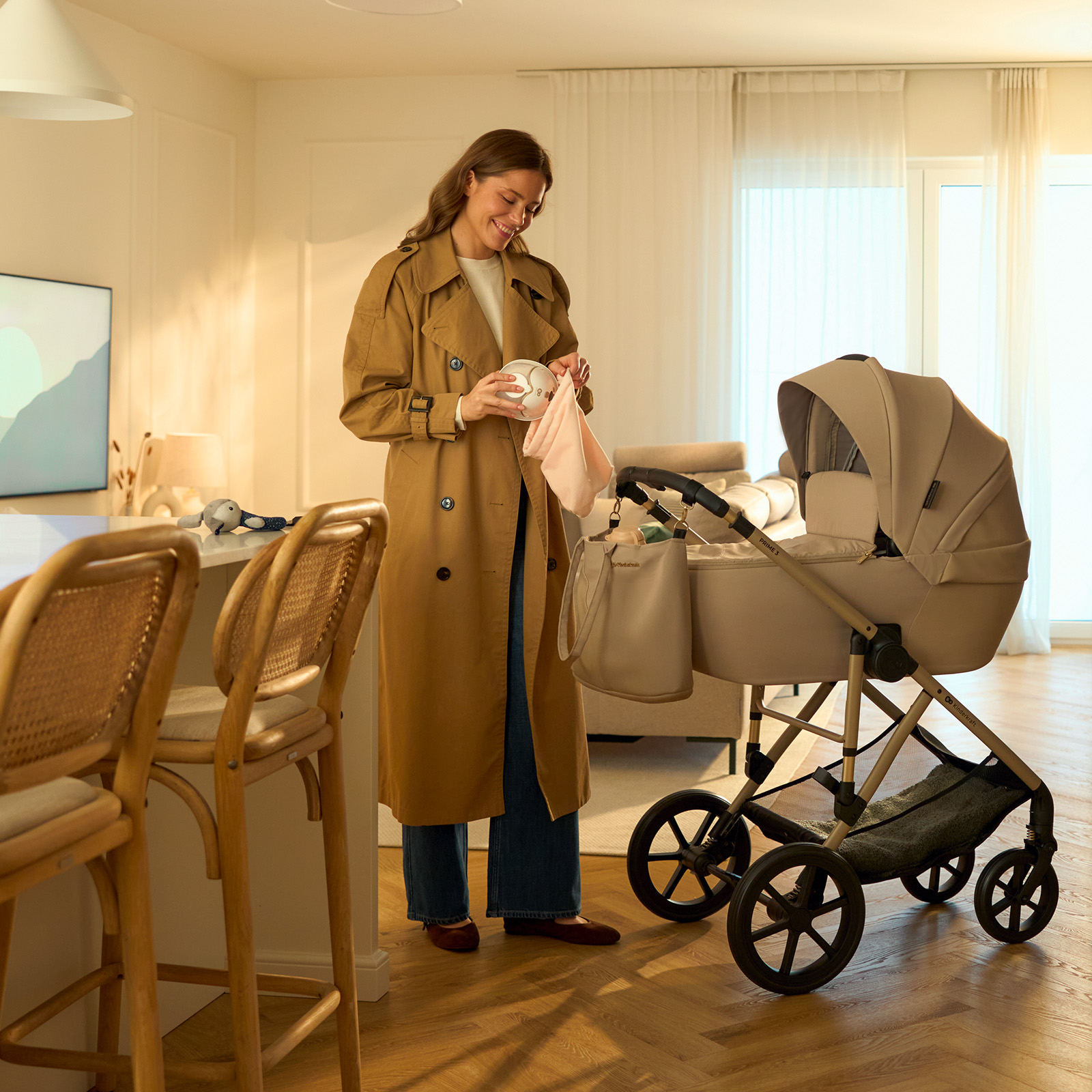 Frau in beigem Mantel packt Kinderwagen mit Wickeltasche.