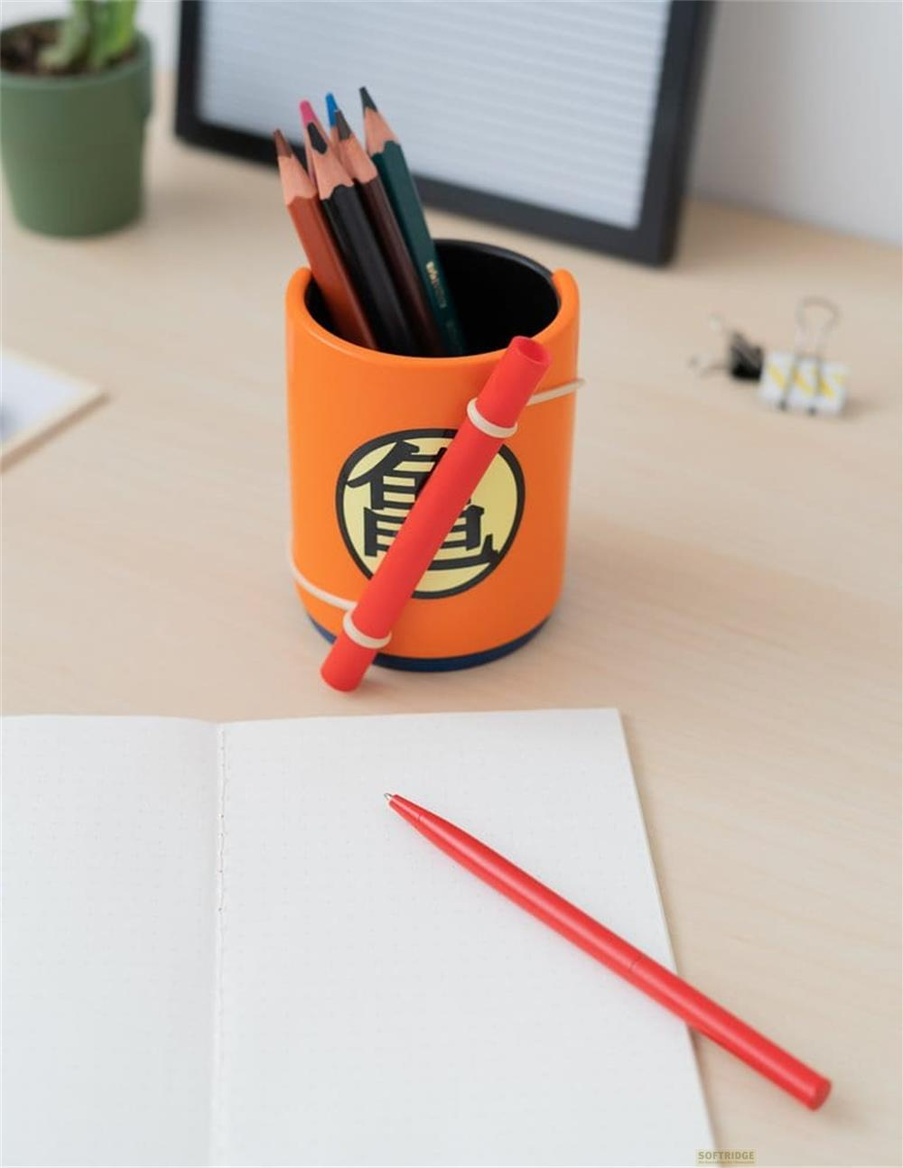 Orange Stiftehalter mit Dragon Ball Z Logo, Stiften und rotem Stift auf Notizbuch.