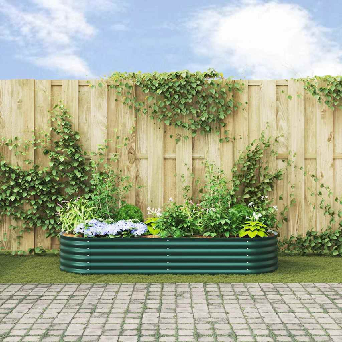 Un'aiuola rialzata verde con piante si trova su un sentiero lastricato davanti a una recinzione di legno.