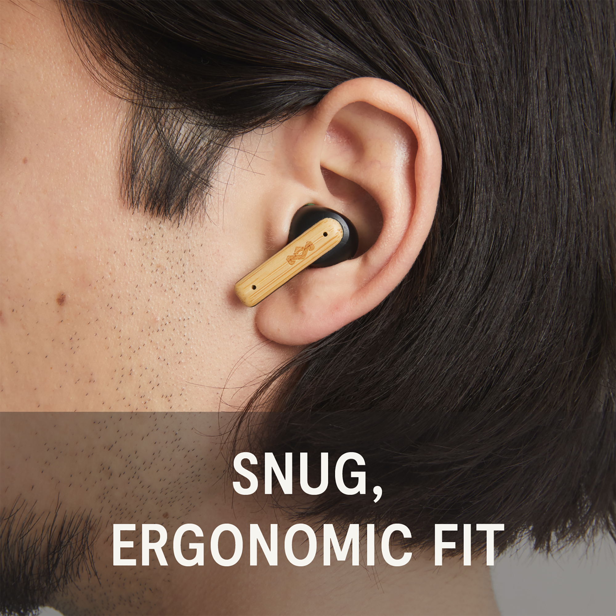 Ein schwarzer In-Ear-Kopfhörer mit Bambusdetail im Ohr eines Mannes.