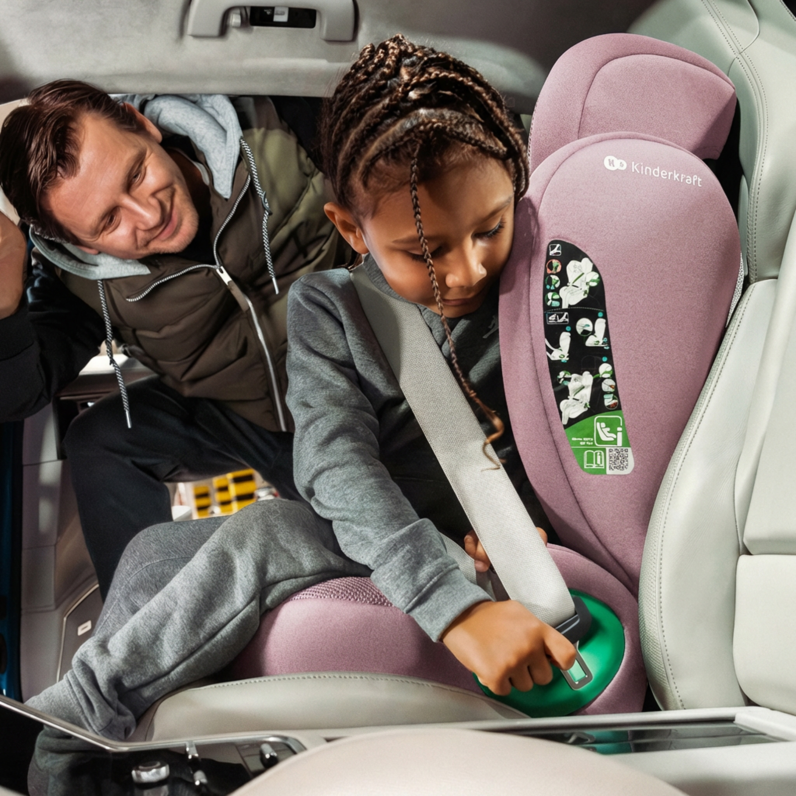 Ein Mann hilft einem Mädchen, sich im Auto anzuschnallen, in einem rosafarbenen Autositz.