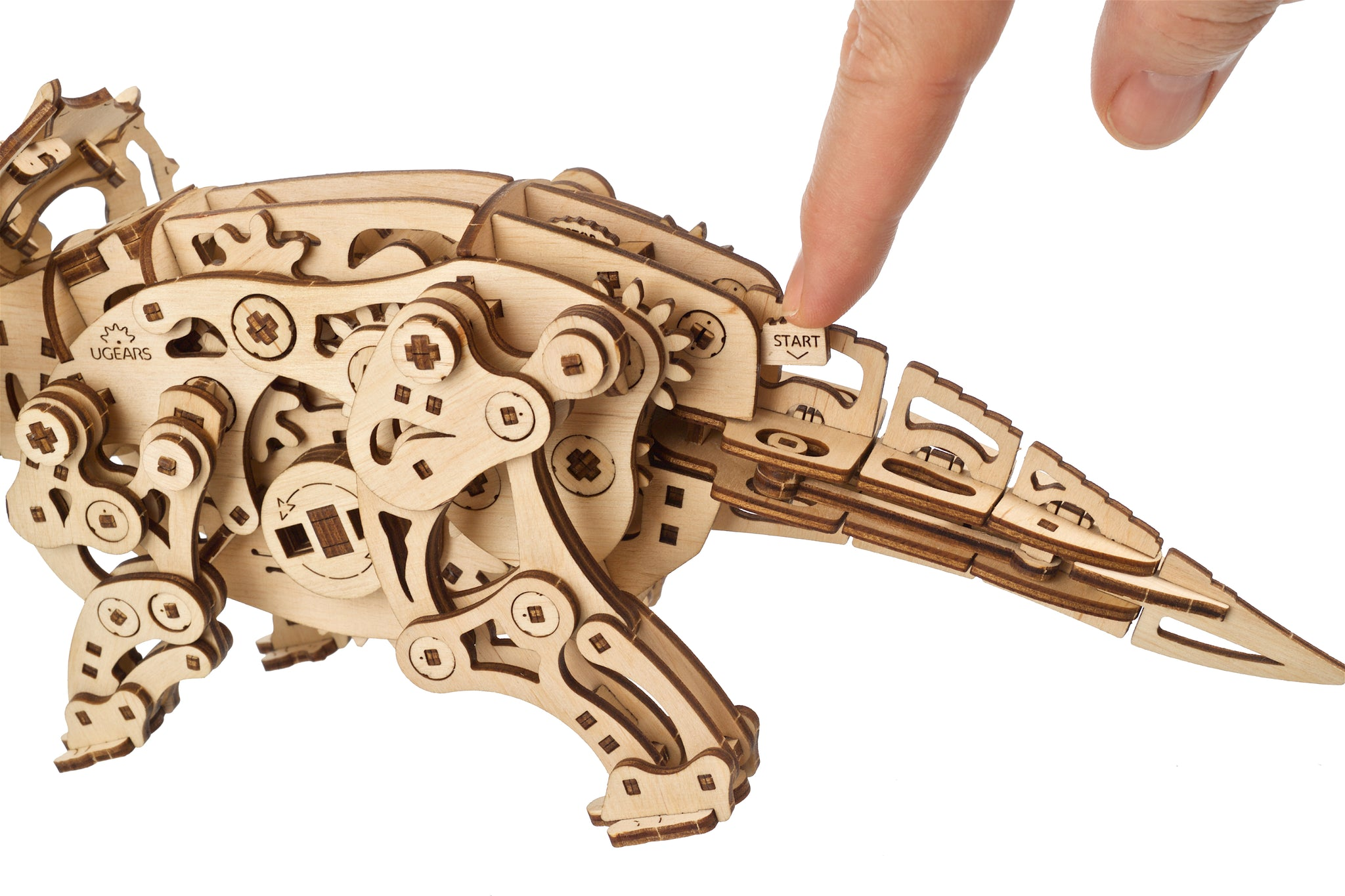 Ein Finger drückt auf einen Holzmechanismus mit der Aufschrift 'START'.