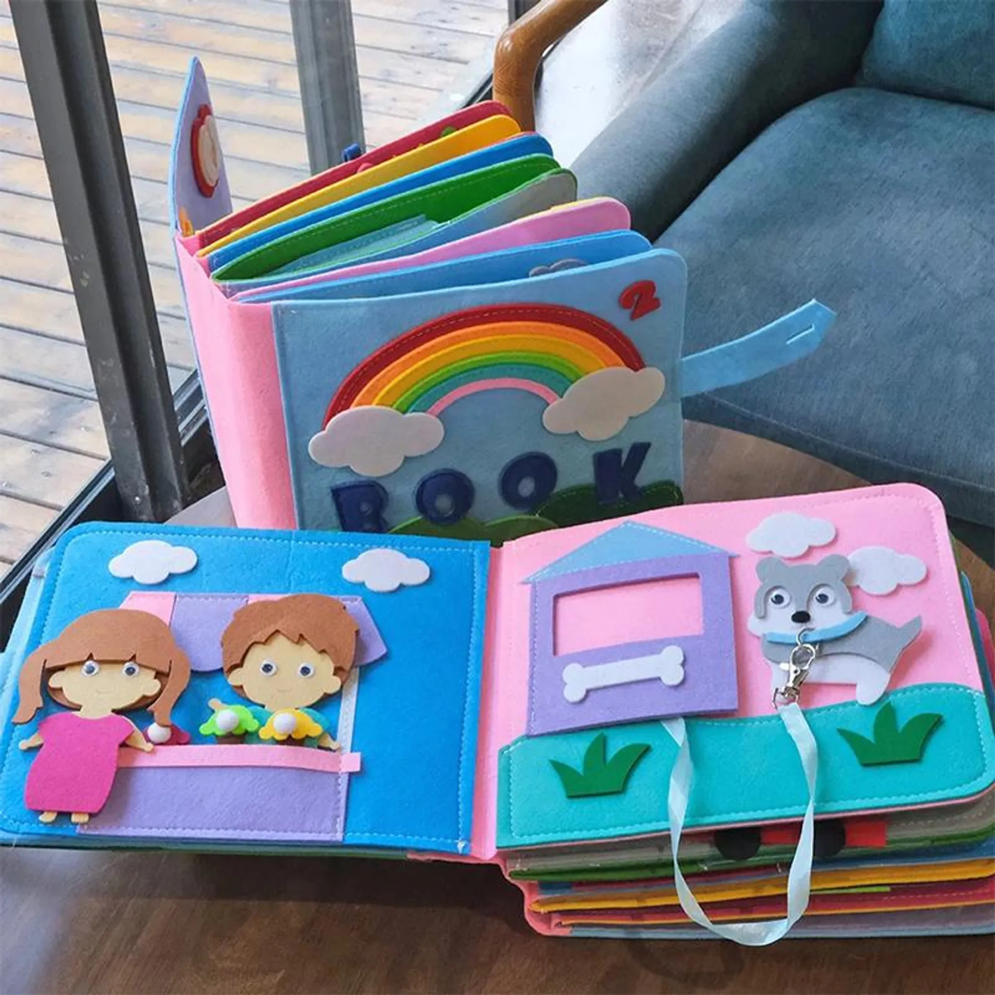 Buntes Stoffbuch mit Regenbogen, Kindern und Hund. Offen auf einem Holztisch.