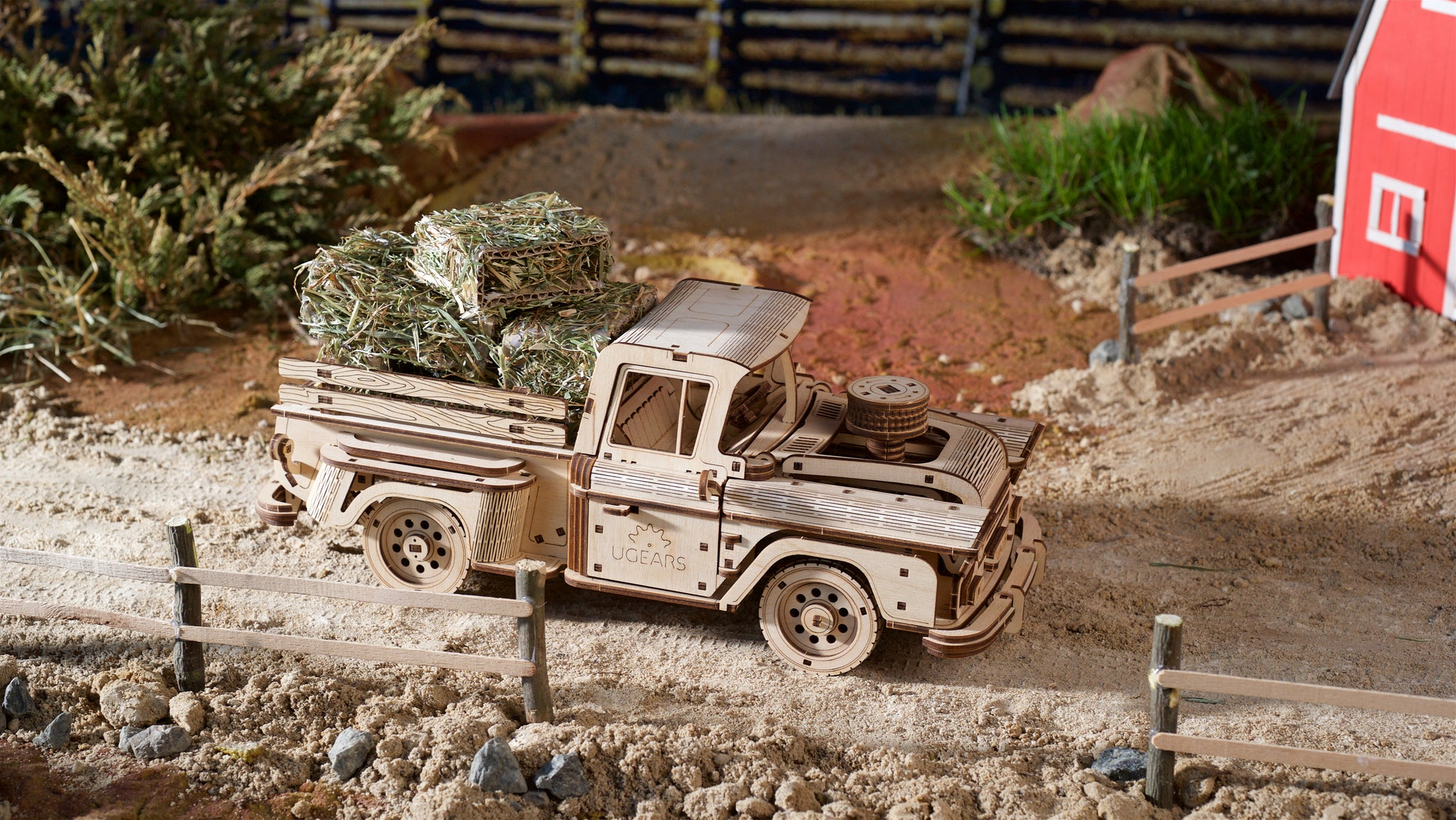 Ein Holzmodell eines Pickups mit Heuballen beladen, auf einem Modellbau-Bauernhof.
