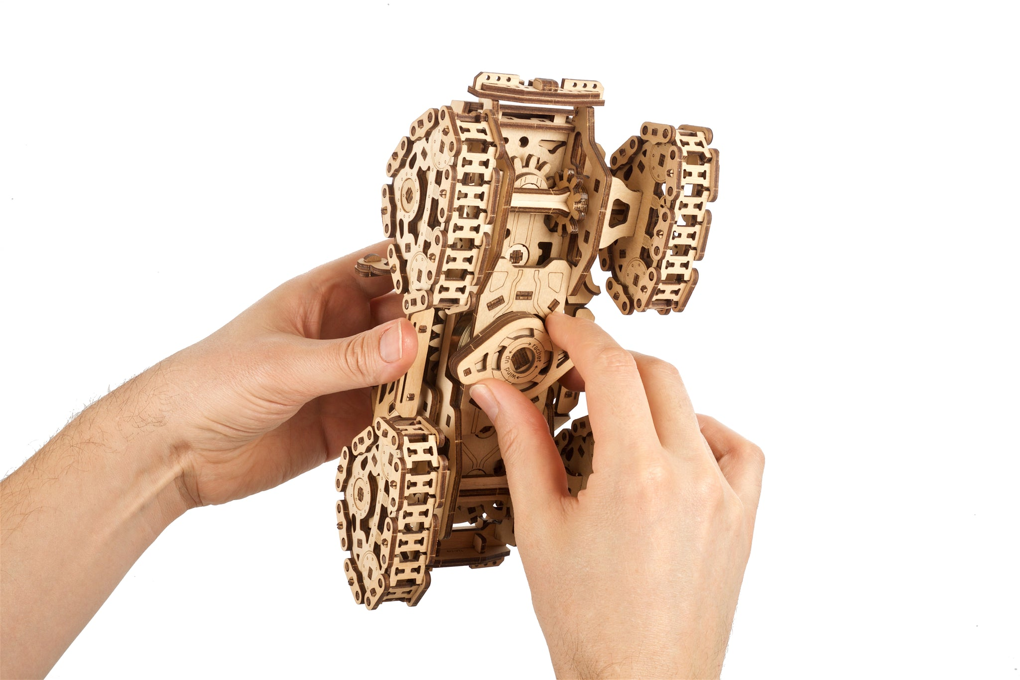 Mani che assemblano un modello di carro armato di legno con cingoli.