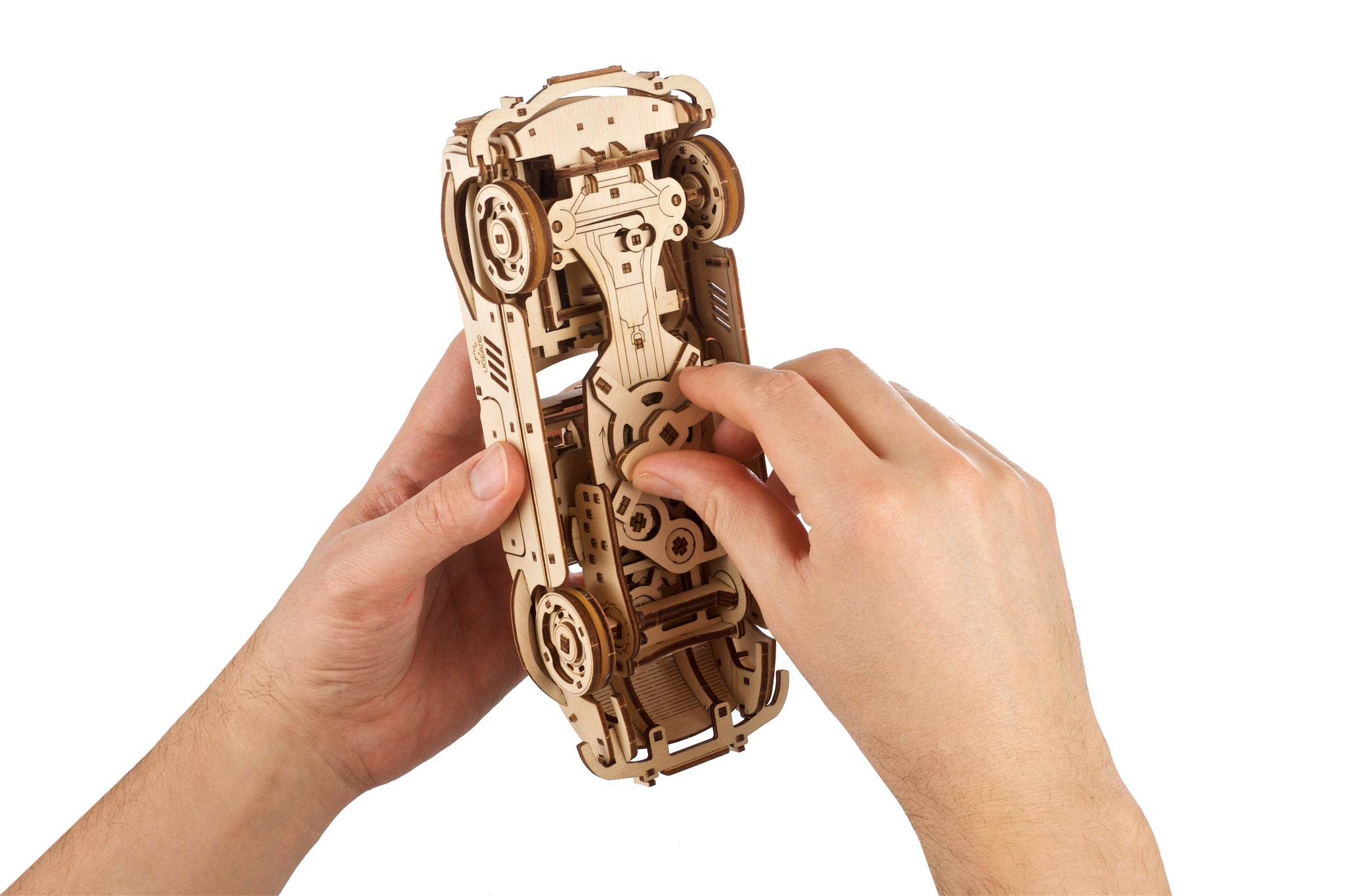 Mani tengono un'auto modello in legno, costruita con blocchi di legno.