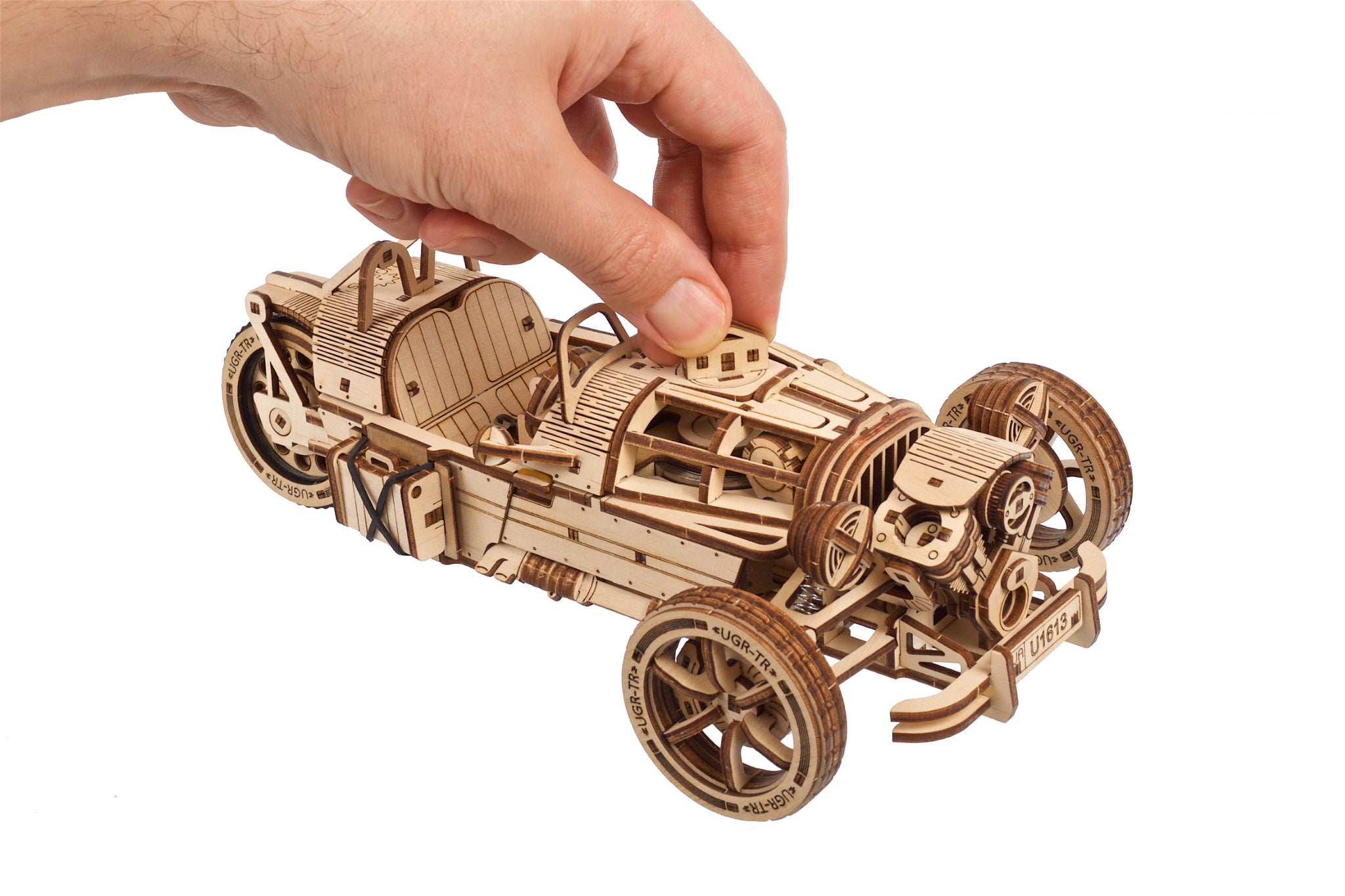 Una persona assembla un modello in legno di un'auto da corsa d'epoca.
