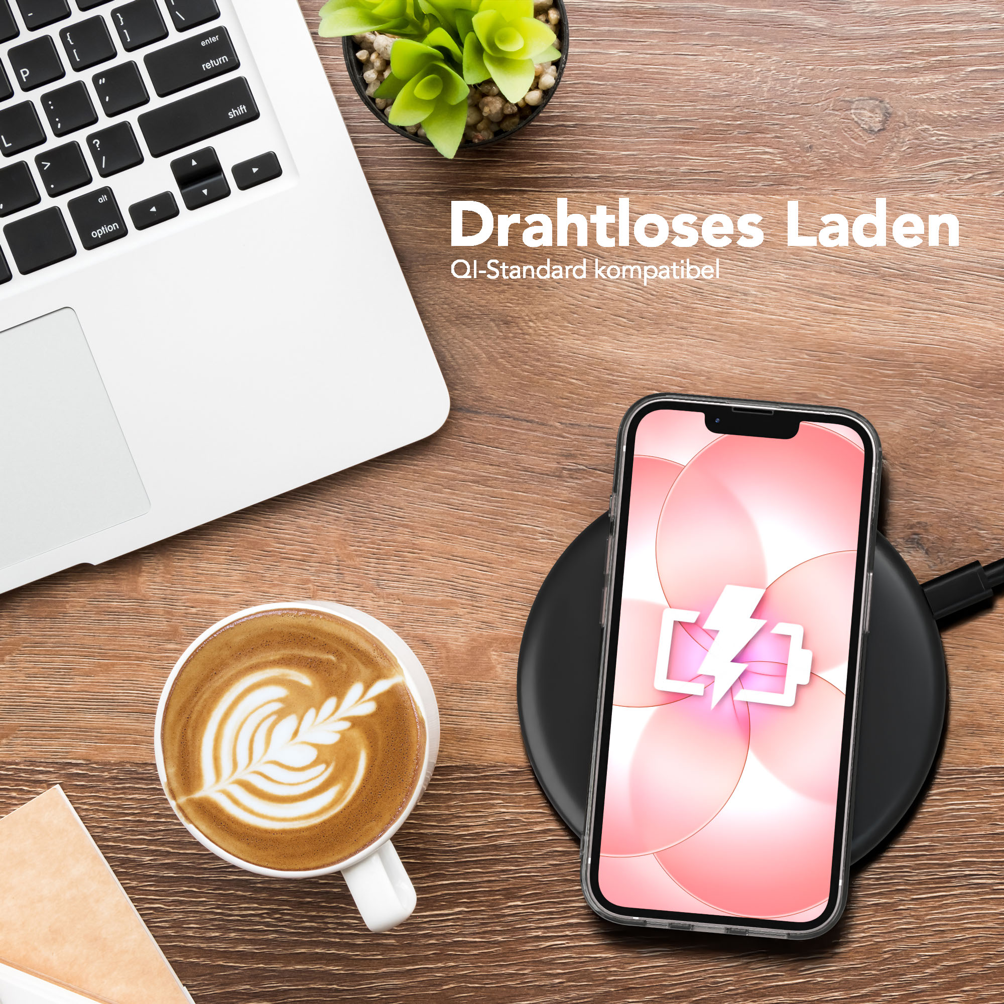 Ein Laptop, eine Kaffeetasse und ein Handy auf einem Ladegerät auf einem Holztisch.