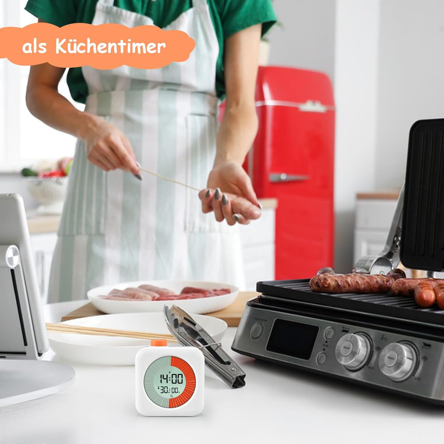Eine Person kocht Würstchen auf einem Grill. Ein digitaler Timer ist auf dem Tisch.