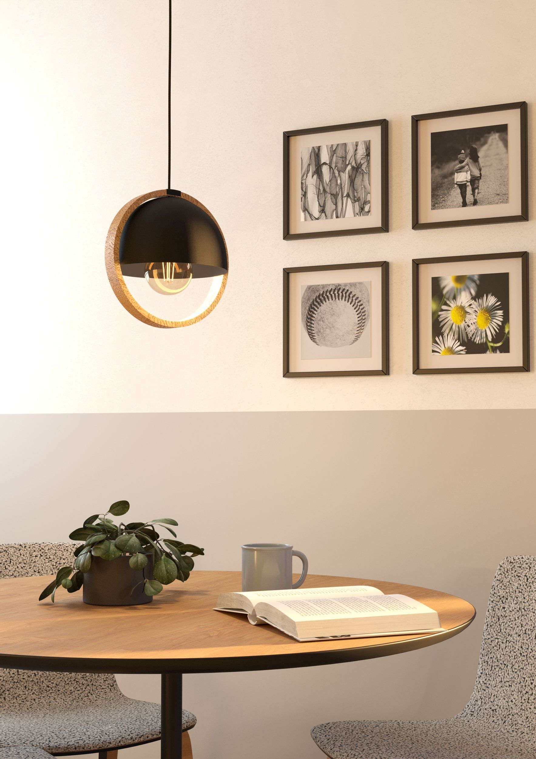 Area pranzo moderna con lampada a sospensione, quadri, pianta, libro aperto e tazza.