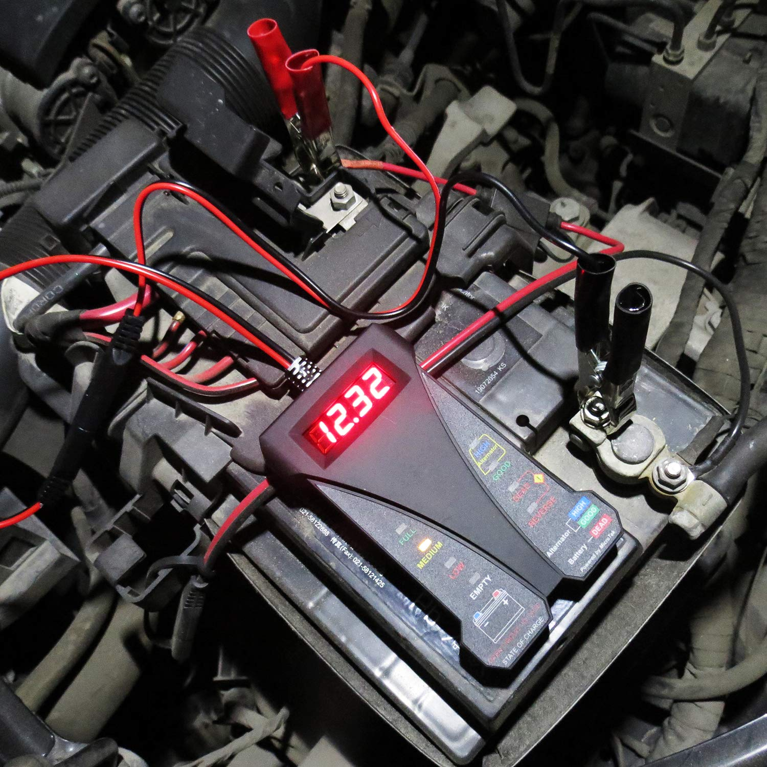 Autobatterietester mit roten und schwarzen Klemmen, die an die Batterie angeschlossen sind.
