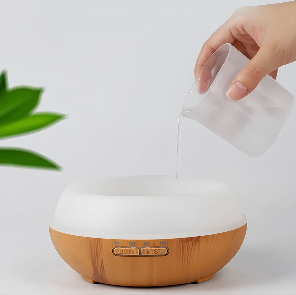 Wasser wird aus einem Behälter in einen holzfarbenen Diffusor gegossen.