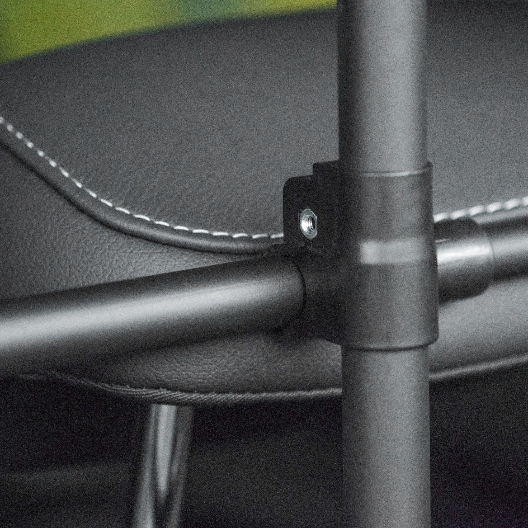 Primer plano de un asiento negro con costuras blancas y estructura metálica.