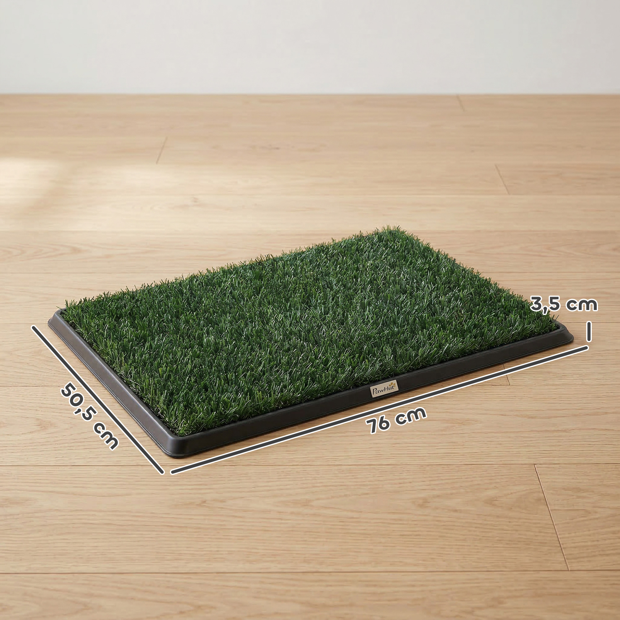 Una alfombrilla rectangular de césped artificial sobre suelo de madera, mide 76x50,5x3,5 cm.