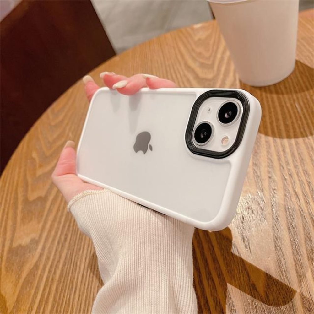 Ahşap masada şeffaf kılıflı beyaz iPhone tutan bir el.