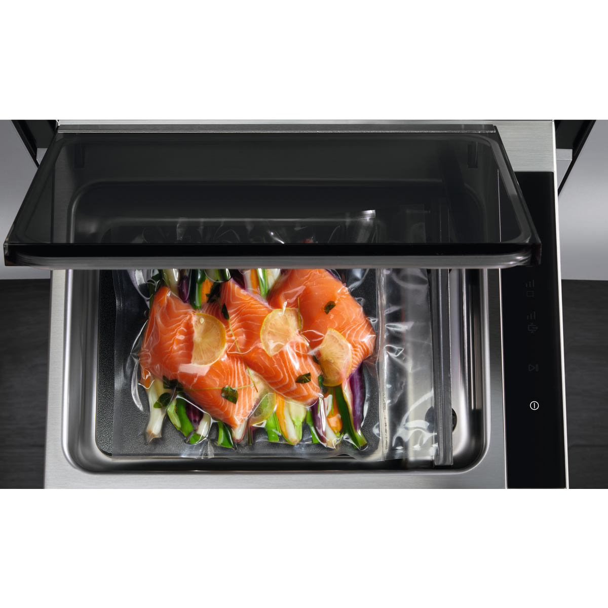 Salmón y verduras en una bolsa de vacío dentro de un electrodoméstico plateado.